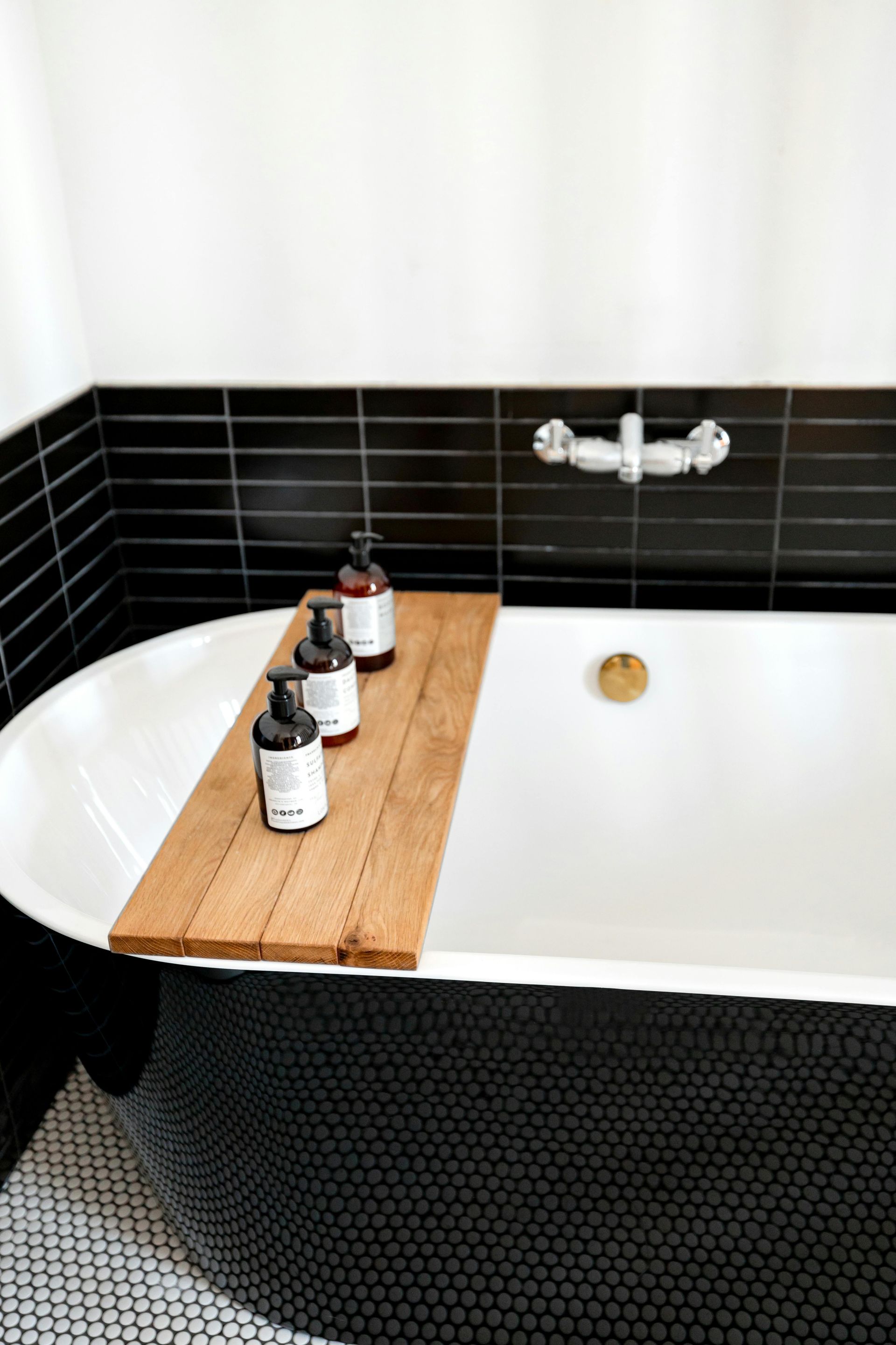 Freestanding soaking tub with wood bath tray and spa-style accessories in a master bath renovation.