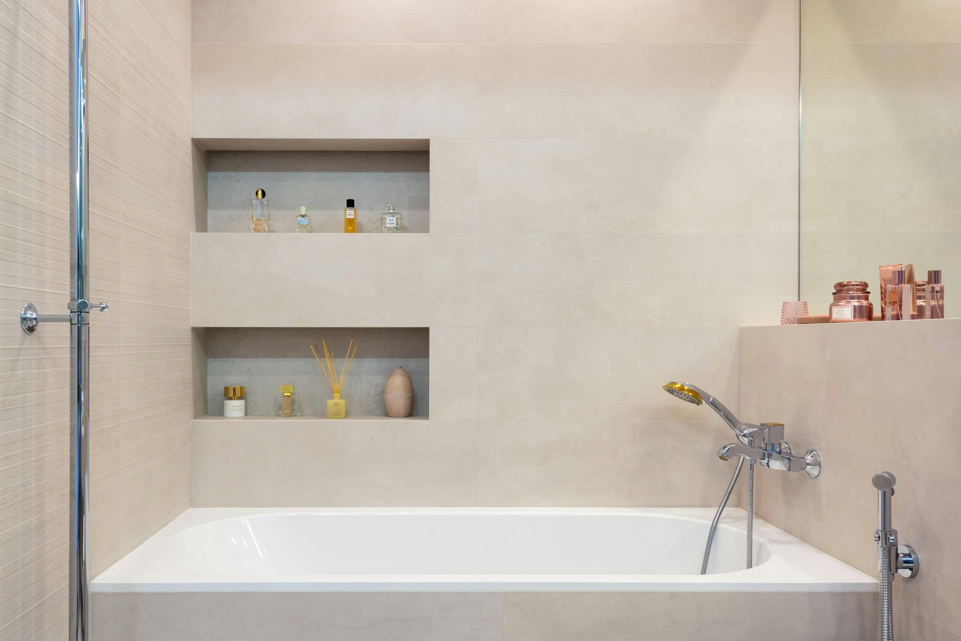 Large-format travertine beige bathroom wall tiles surrounding a tub area with built-in storage.