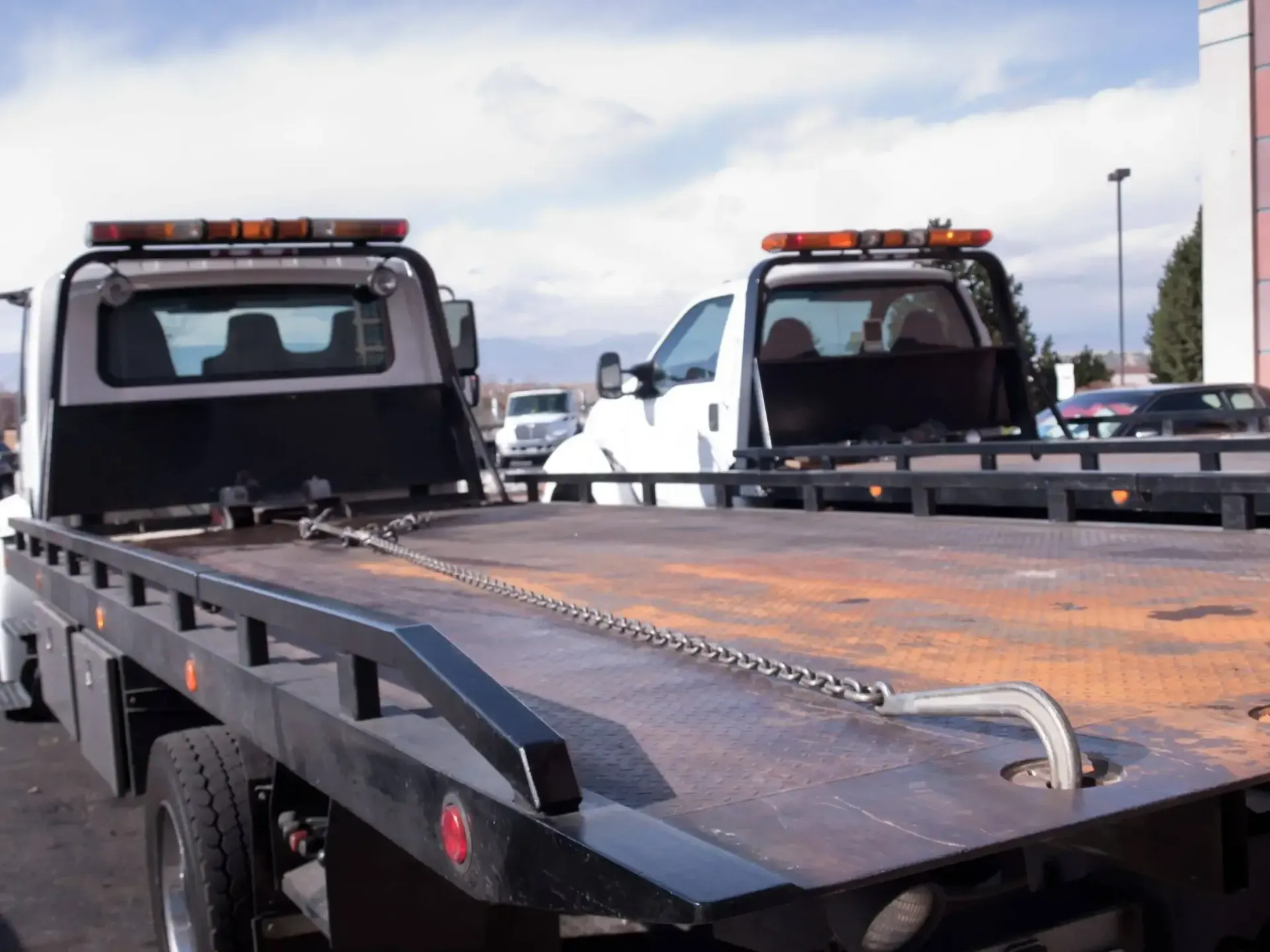 Two tow trucks are parked next to each other in a parking lot.