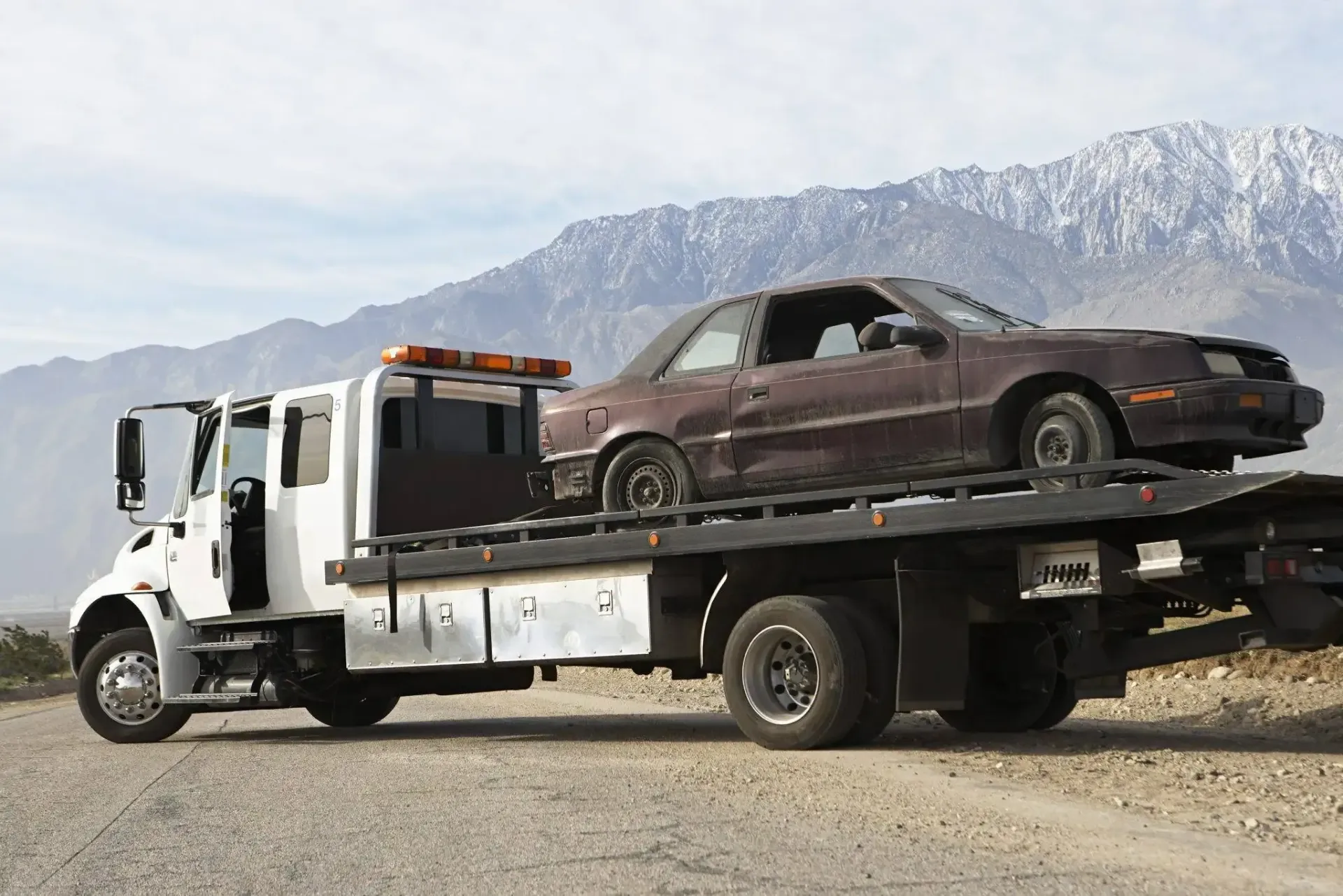A tow truck with a car on the back of it