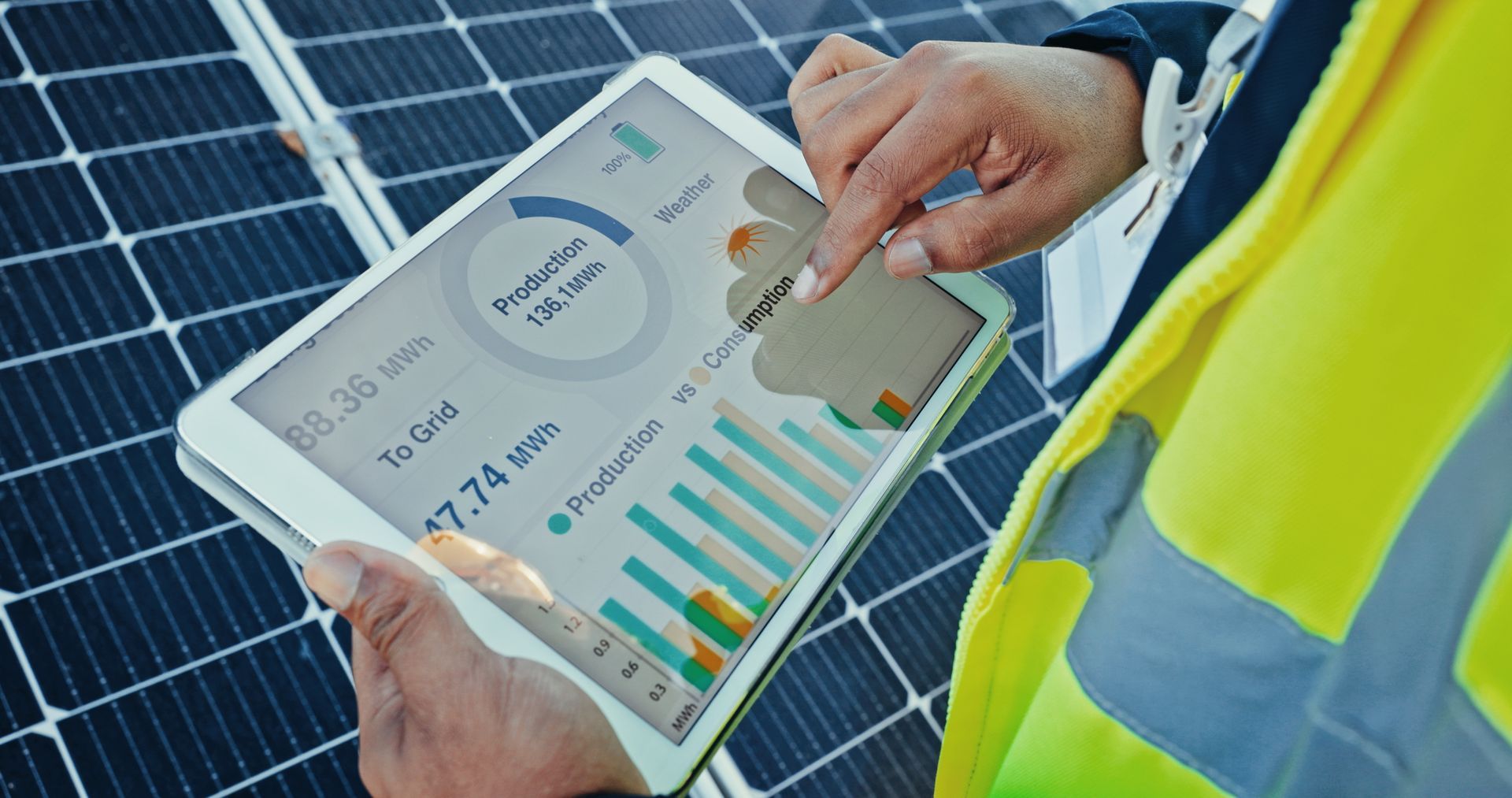 Person in a safety vest using a tablet to monitor solar panel energy production
