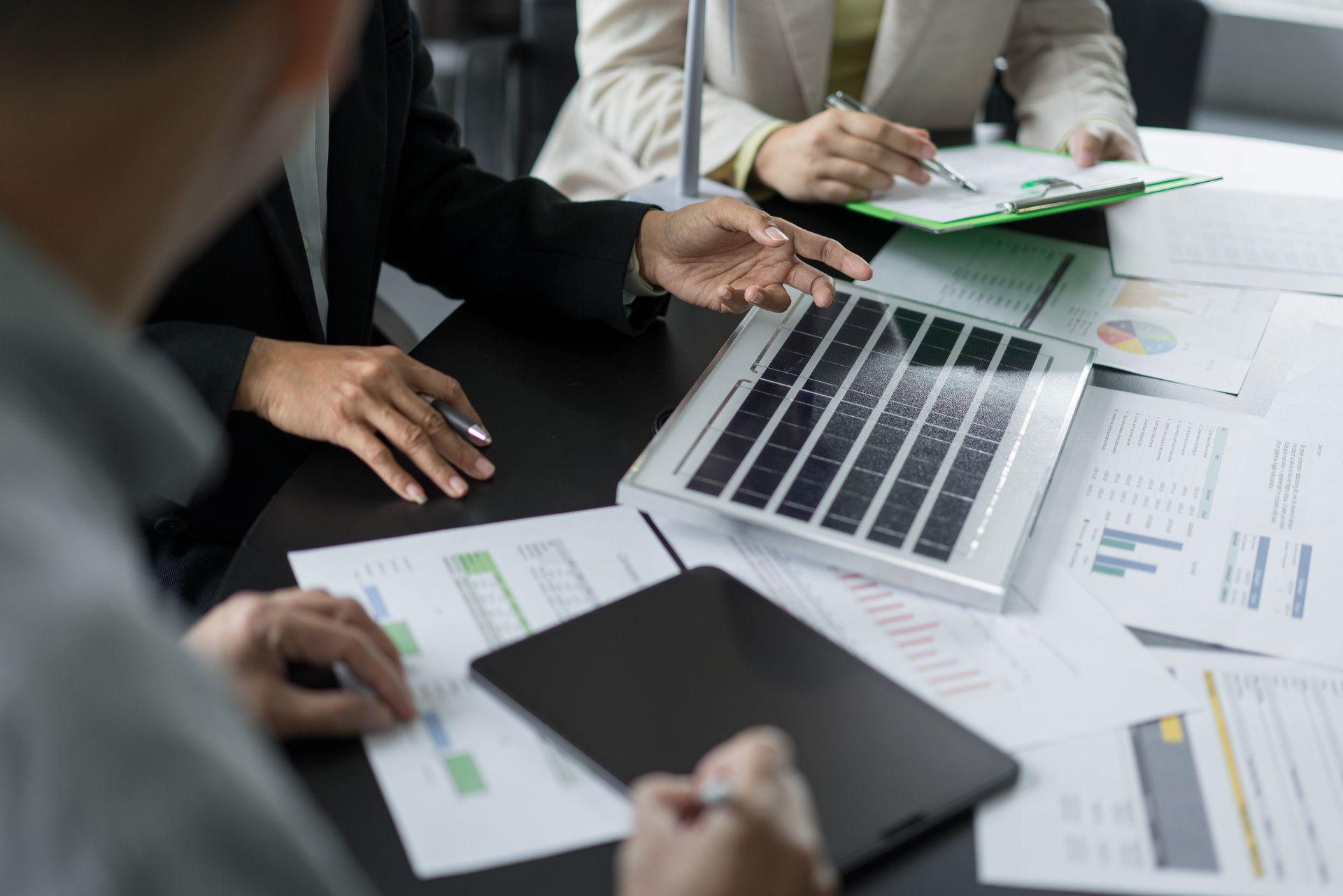 People in business attire reviewing documents and a tablet at a table People in business attire reviewing documents and a tablet at a table