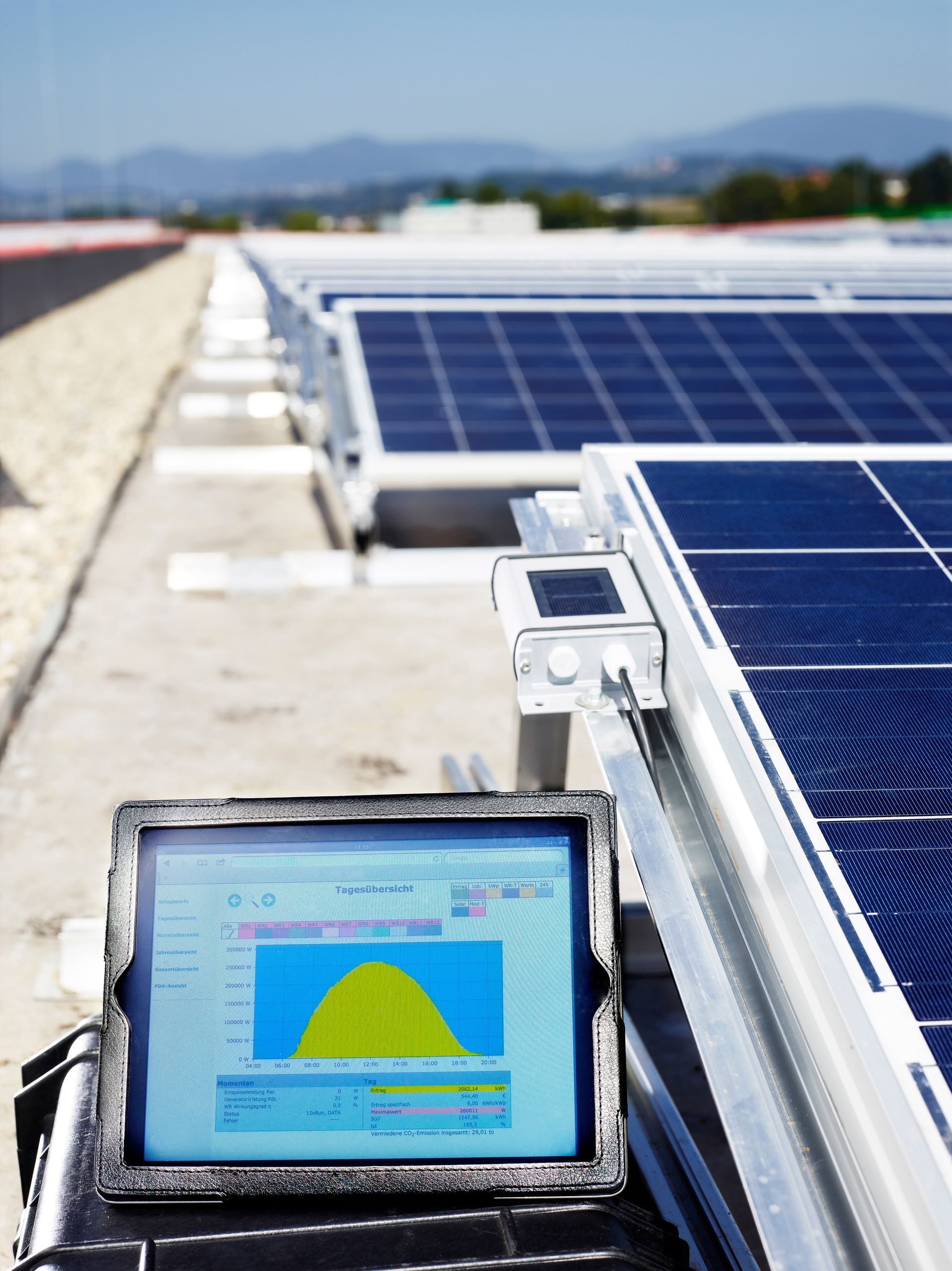 Solar panels on a rooftop, with a monitor displaying performance data