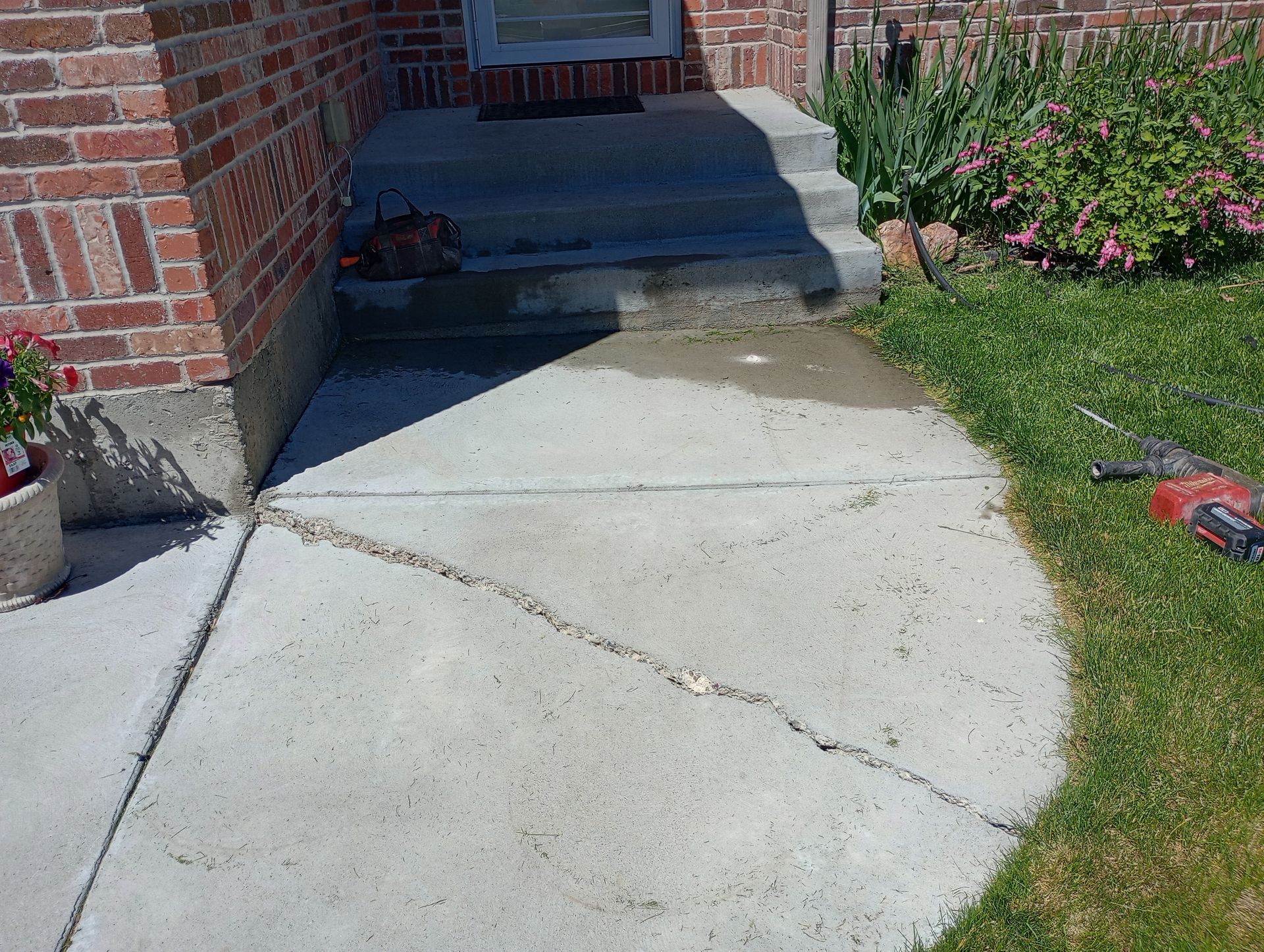 A brick house with a concrete walkway leading to the front door.