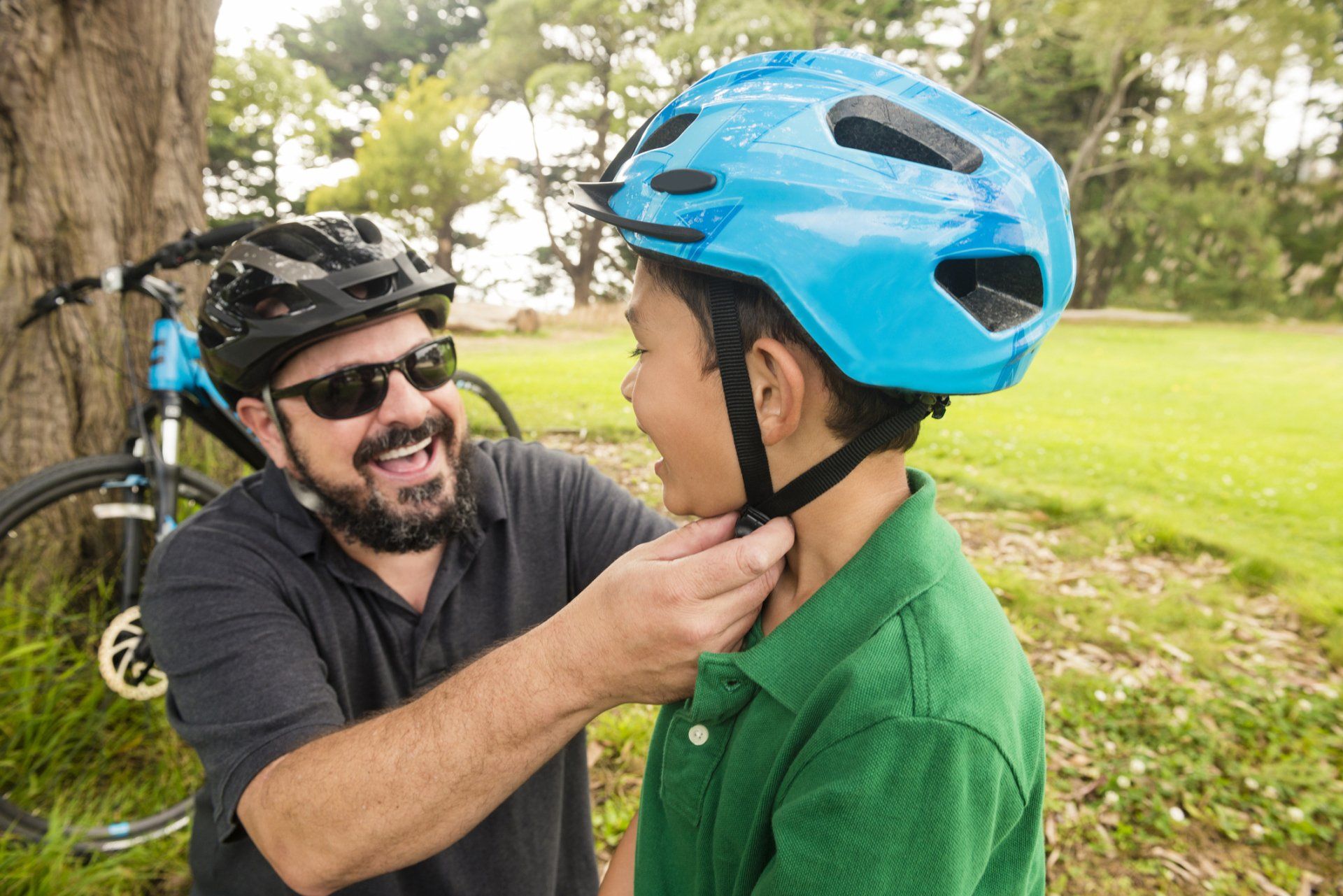 Man putting a bike helmet on kid's head.