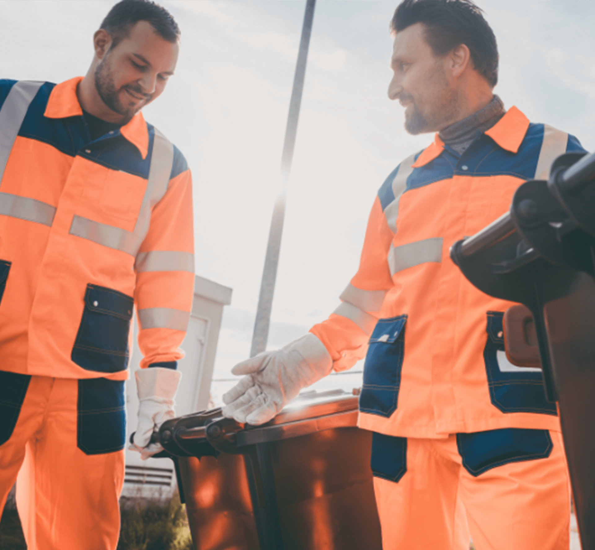 Male workers walking down the street, pushing dustbins ahead of them