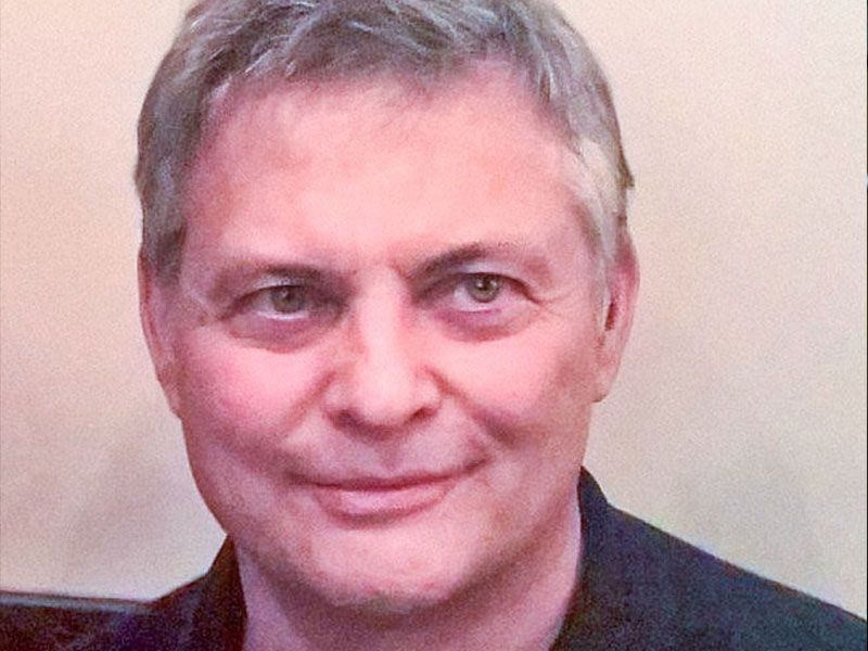 Man with short gray hair, smiling, wearing a dark shirt. Describing Jean-Francios Tremblay.