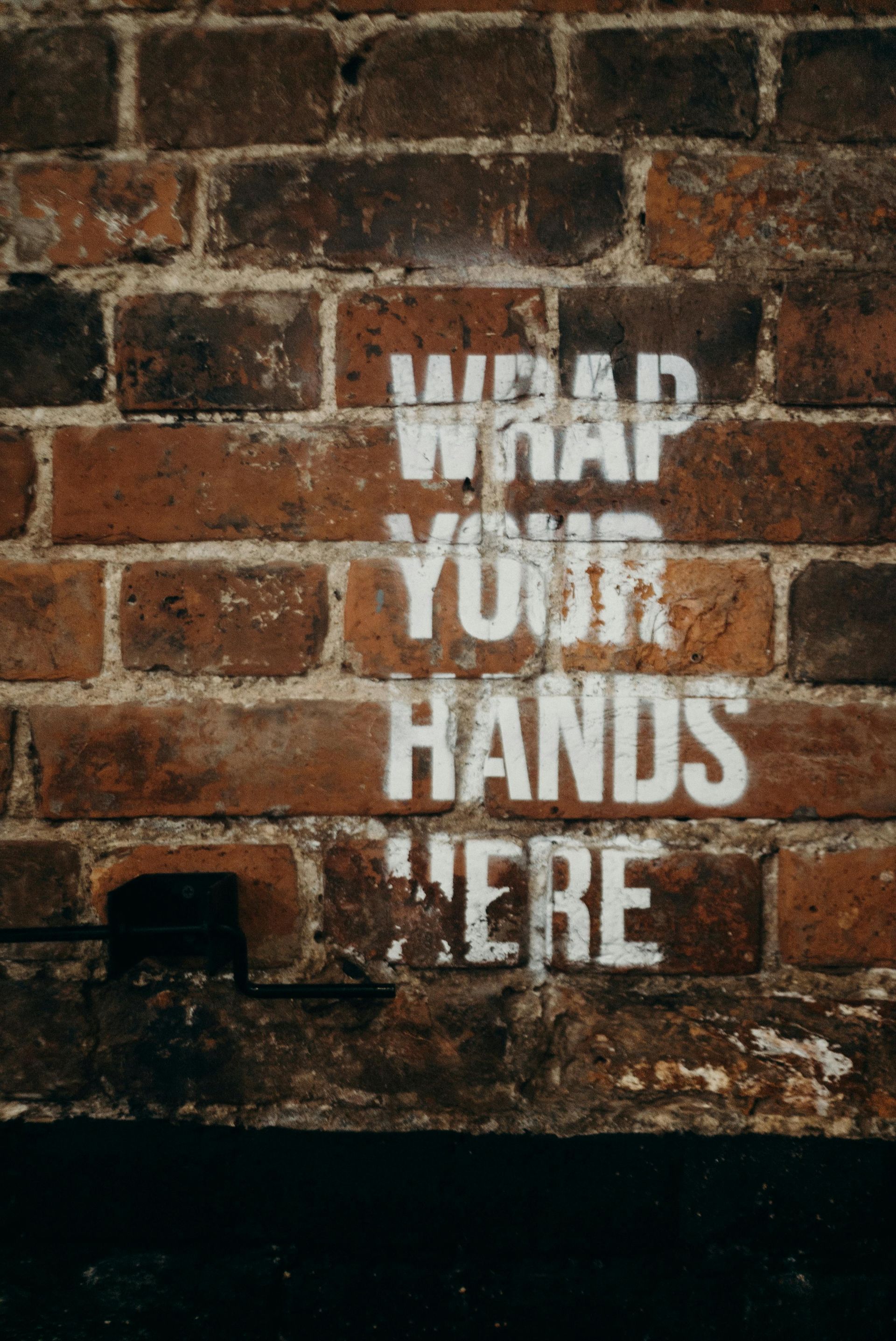 White spray-painted text on a brick wall: