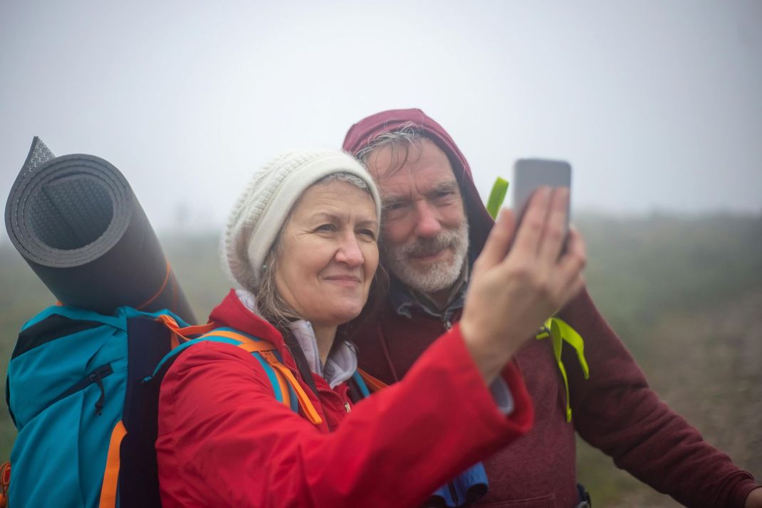 A man and a woman are taking a selfie with a cell phone.