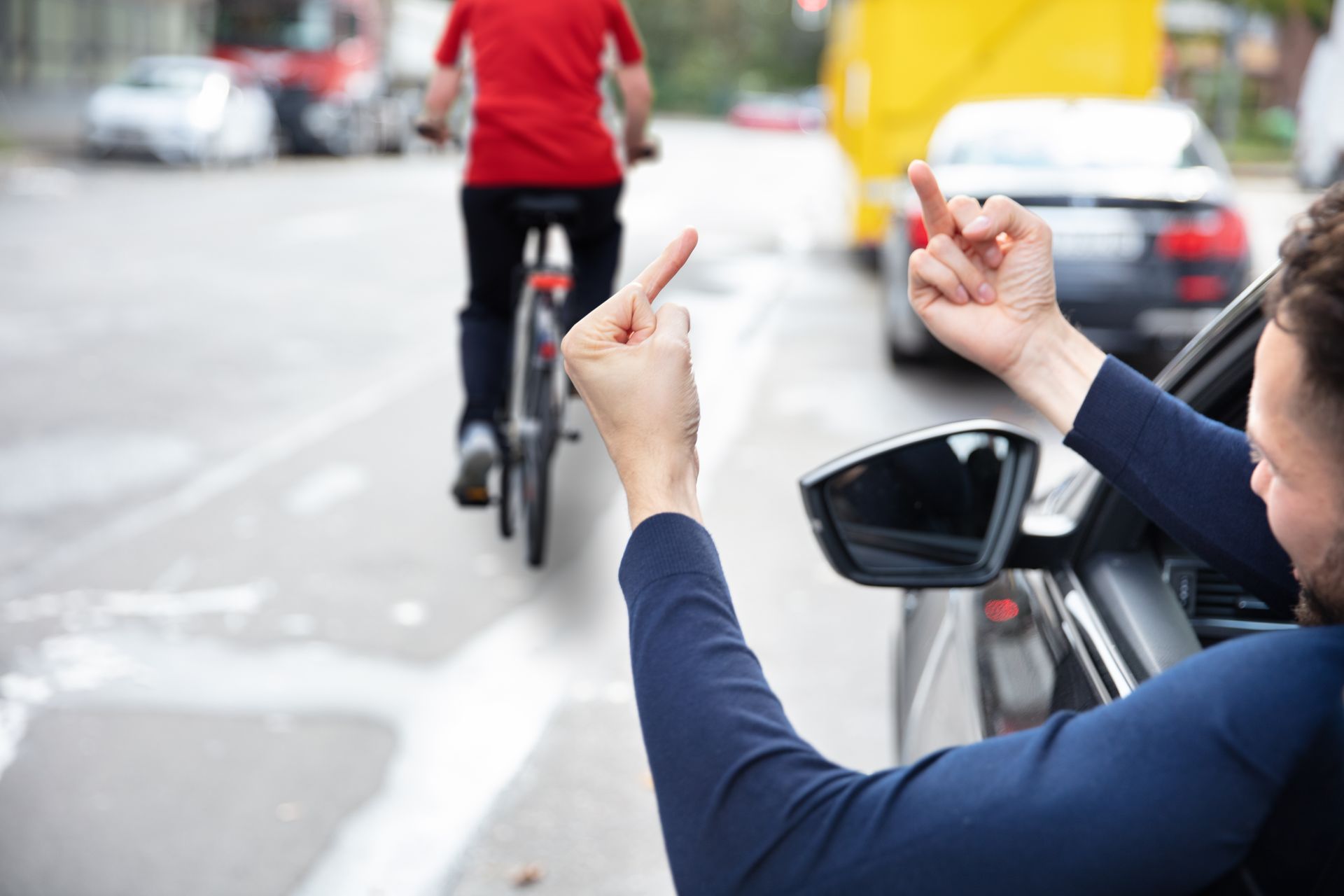 Angry driver giving middle finger to bicycle rider