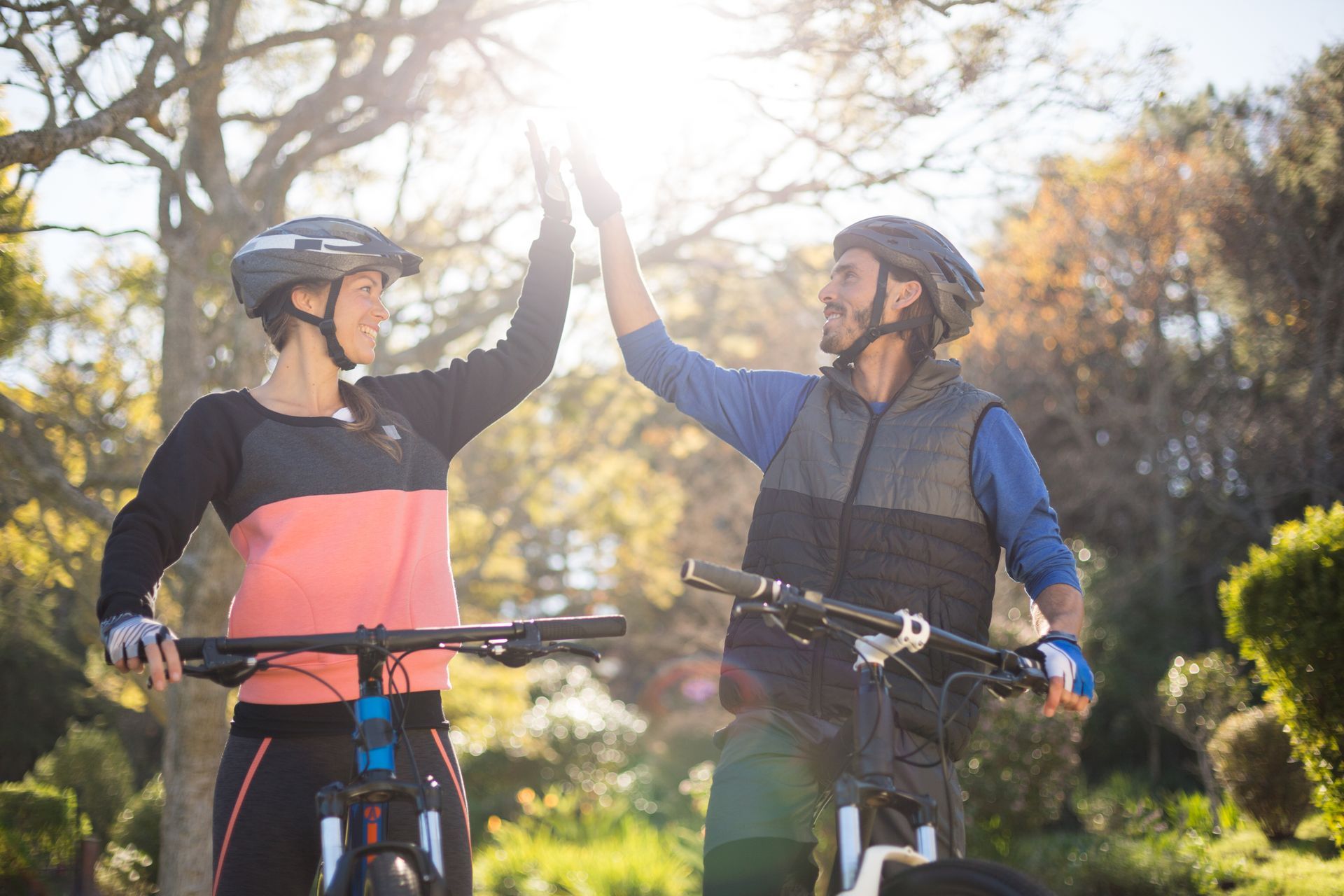 Male and female bicycle riders giving each other the High Five hand gesture, smiling