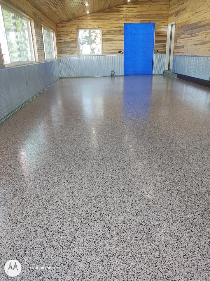 Empty hall with speckled floor, gray paneled walls, wood ceiling, and a bright blue door at the far end