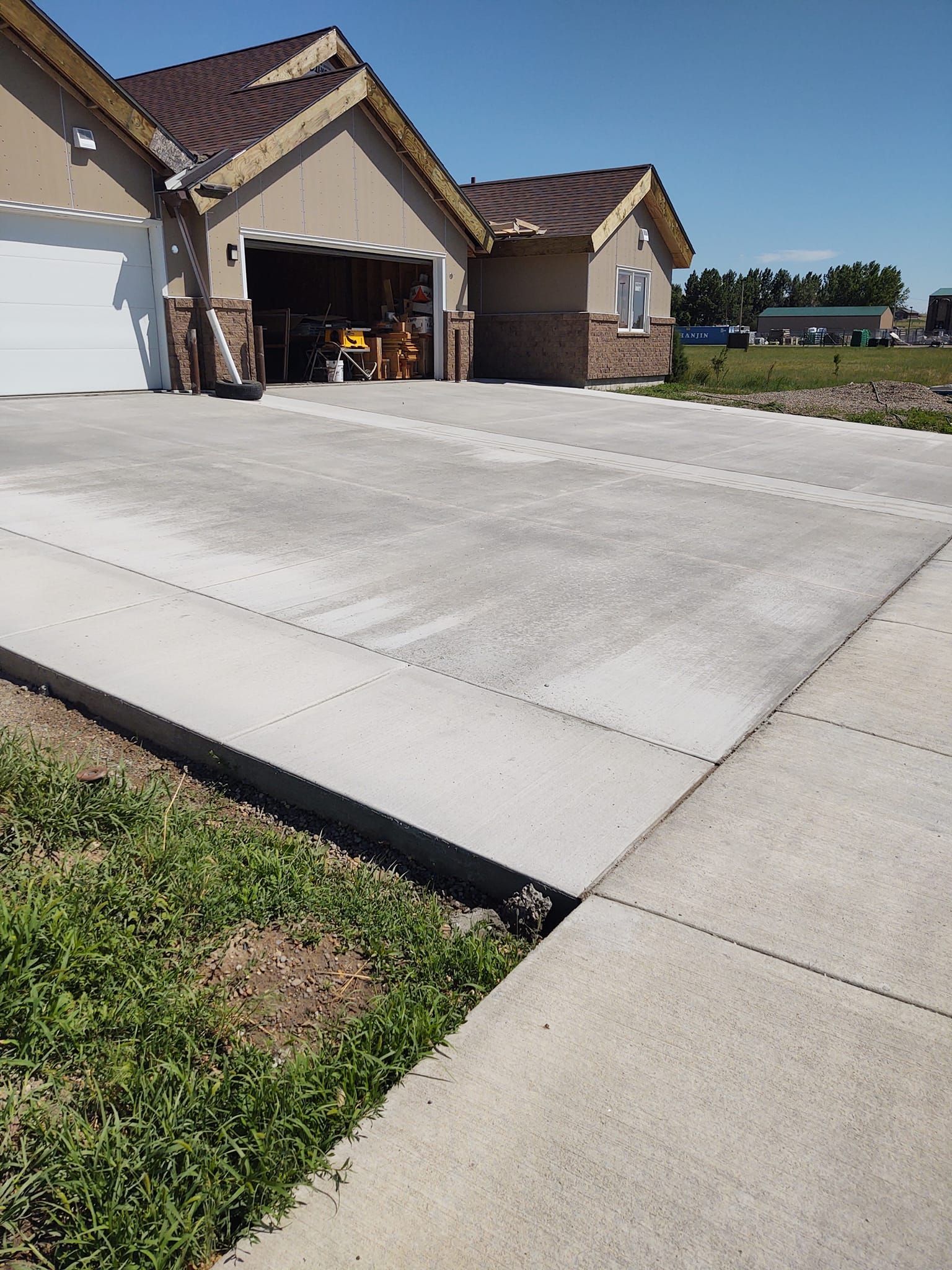 Suburban house with a wide concrete driveway and open garage on a sunny day
