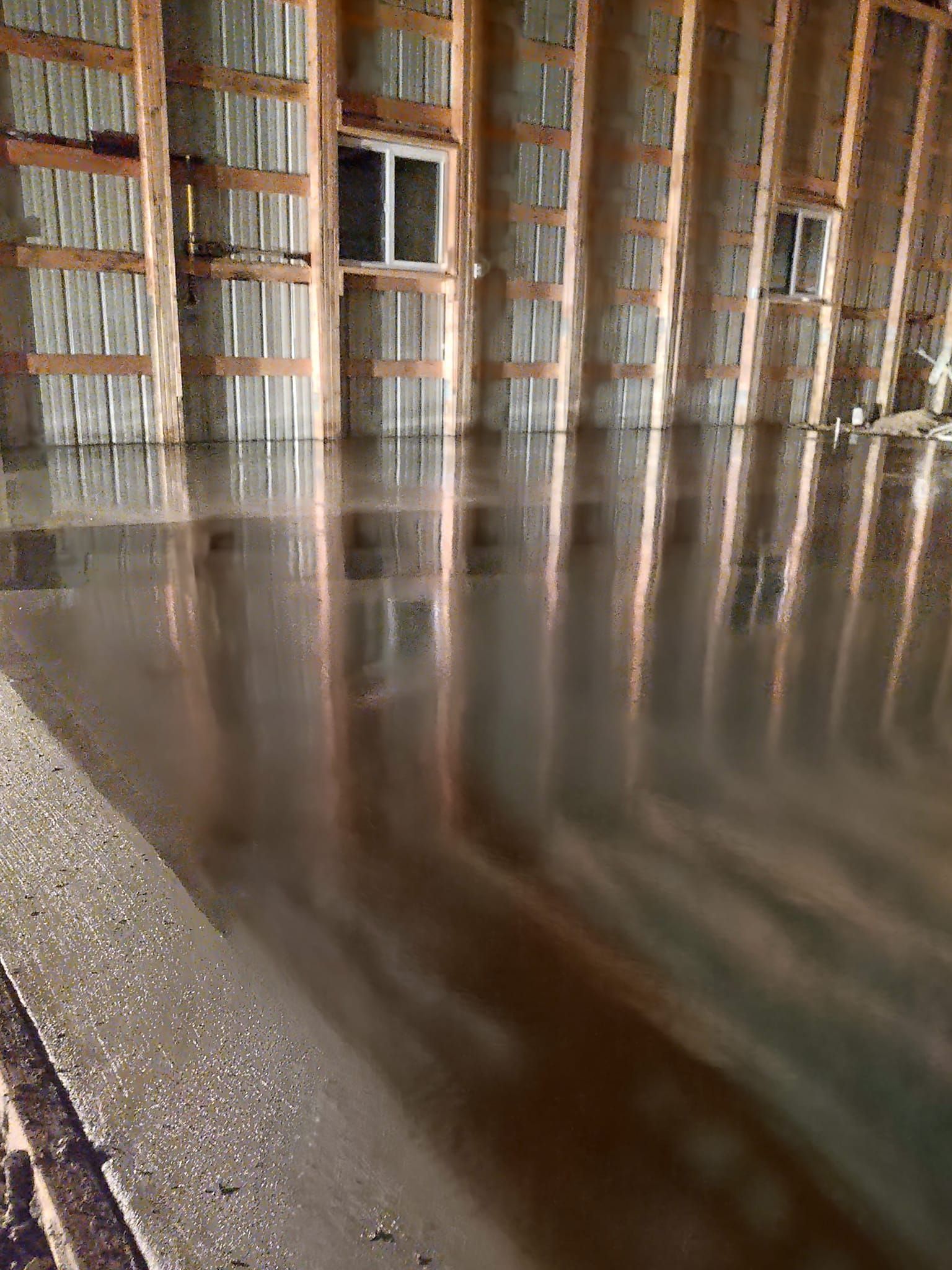 Indoor flooded space with reflective water and rows of tall wooden shelves along the walls