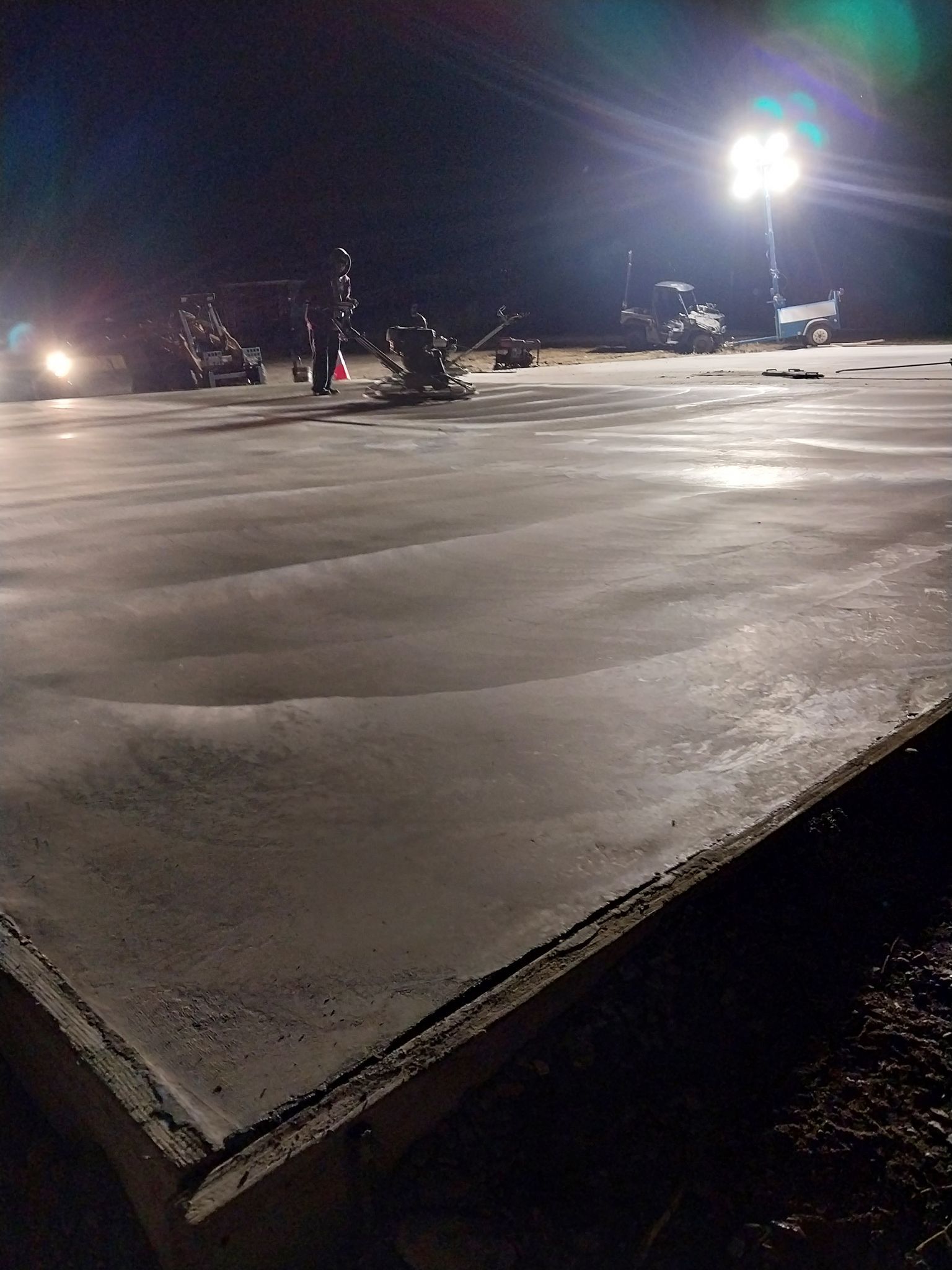Empty nighttime parking lot with bright floodlights and wet pavement reflected in the light