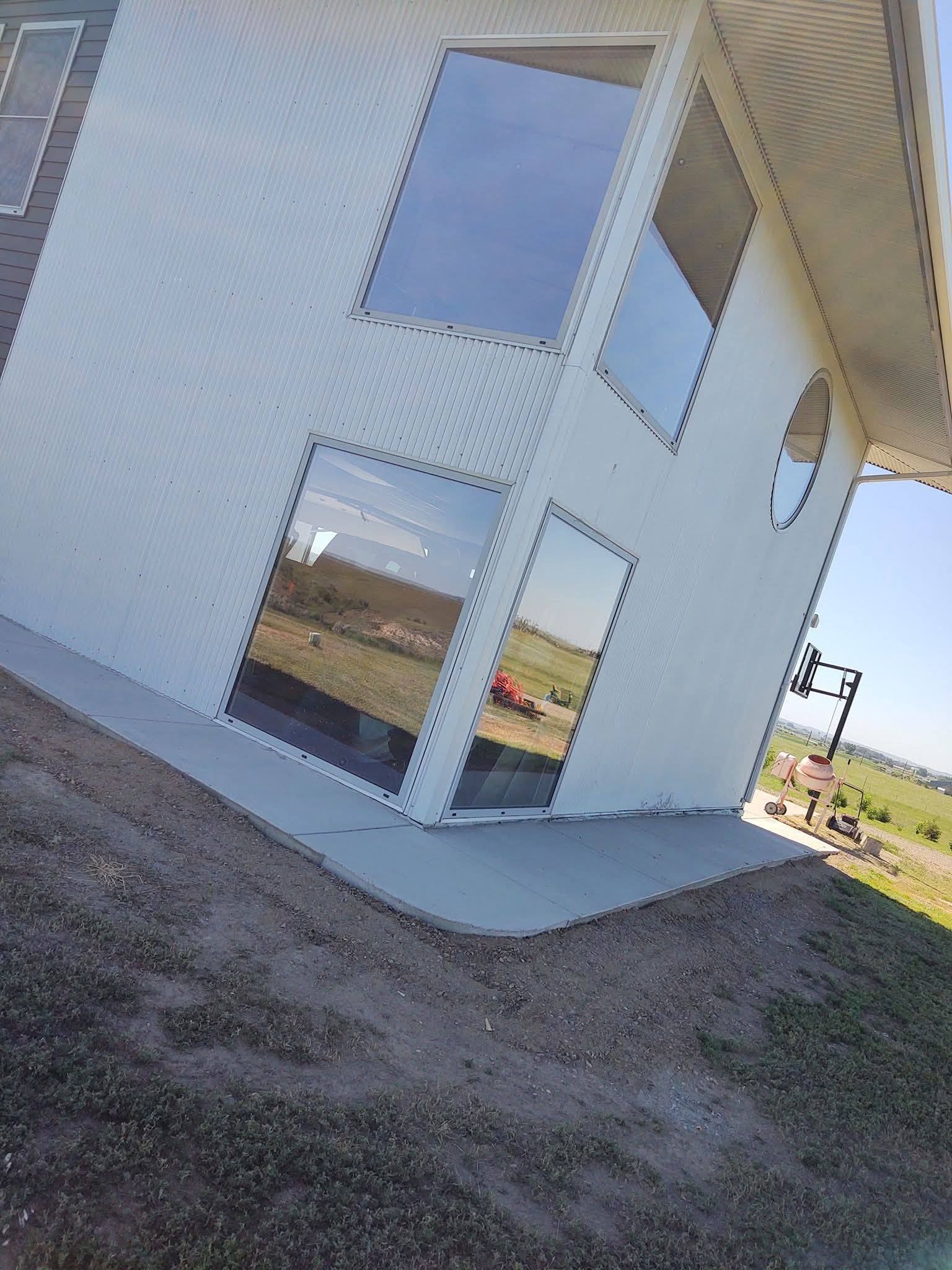 Tilted view of a modern white building with large windows and gravel ground outside