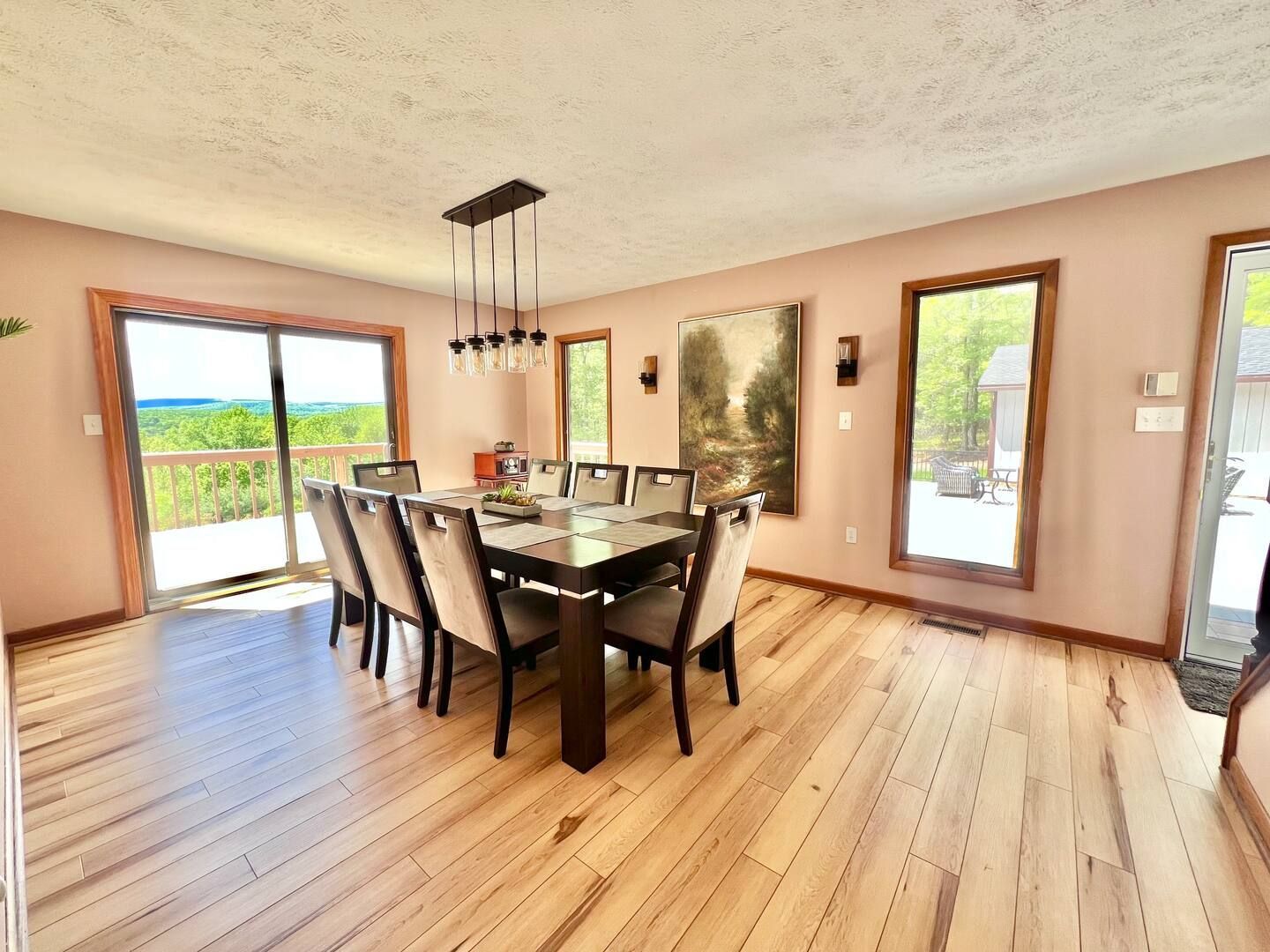 Dining room with large table, chairs, and sliding door overlooking a scenic view.
