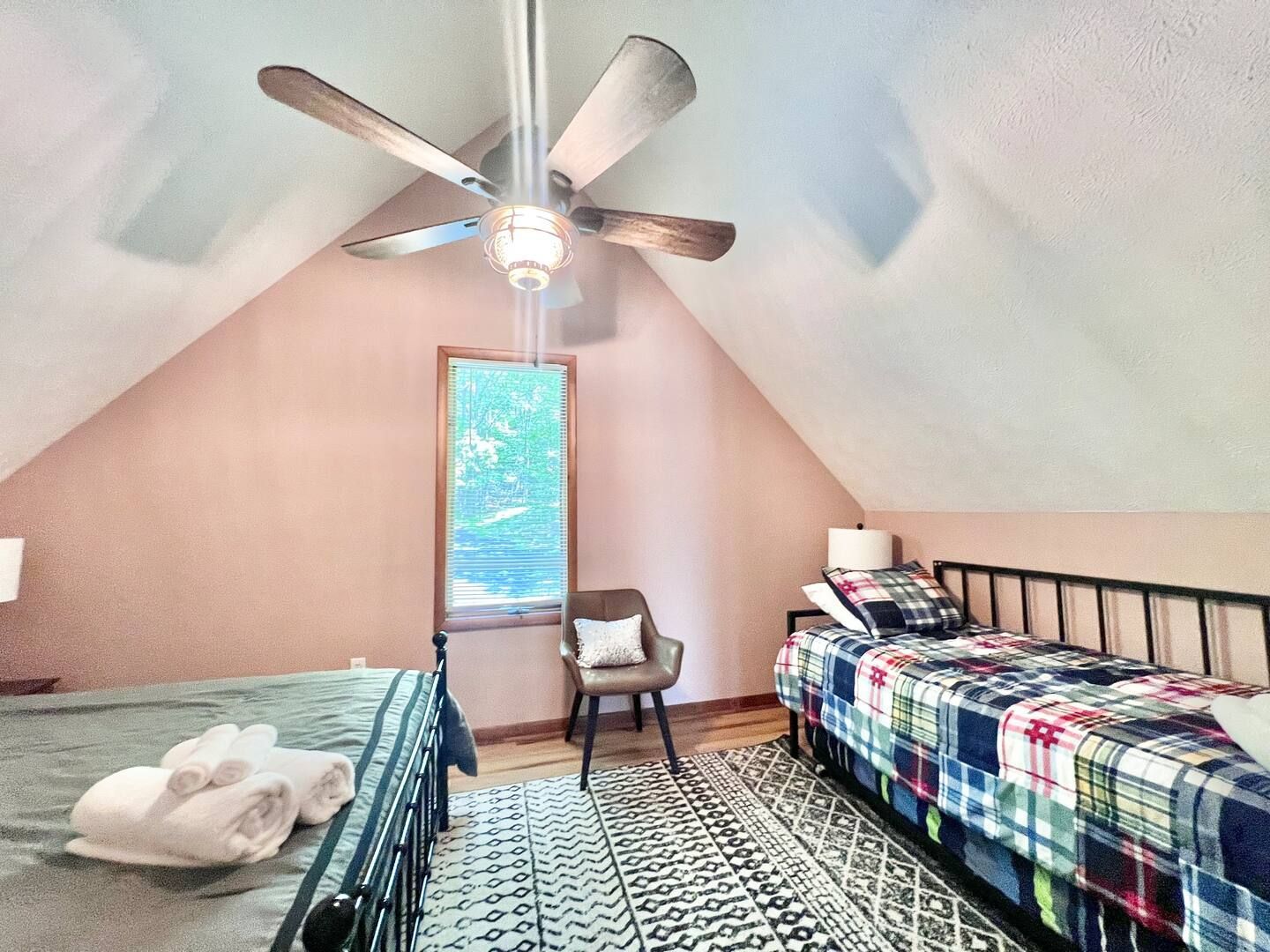 Bedroom with two beds, wood floors, a window, and a ceiling fan.