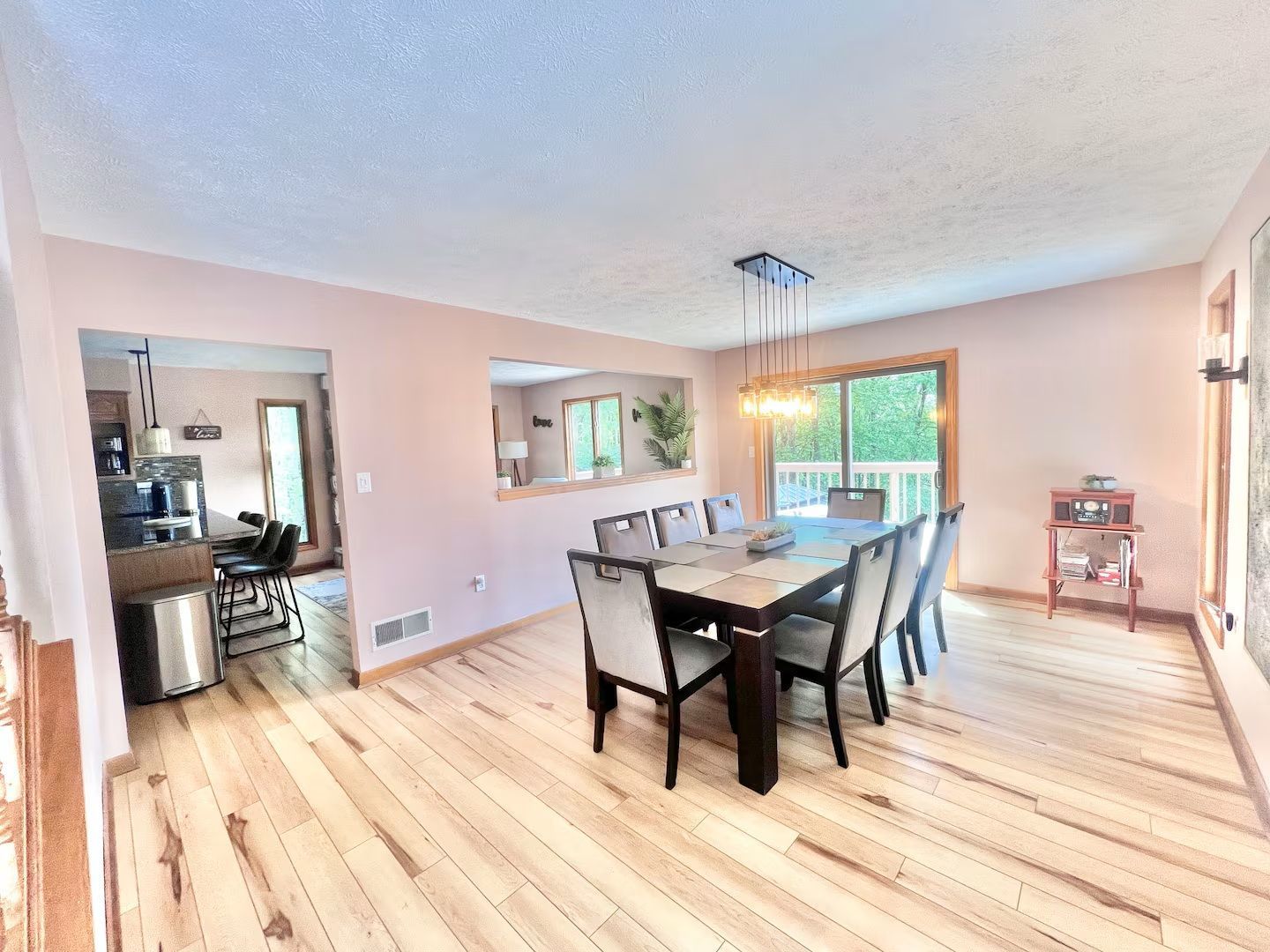 Dining room with wooden floor, table and chairs, and a doorway to the kitchen.
