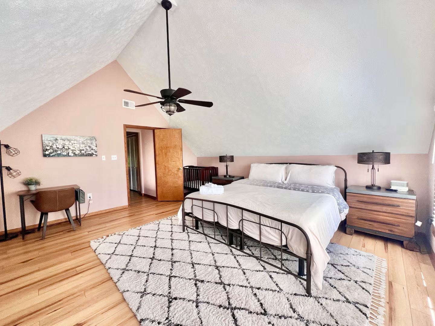 Bedroom with a bed, rug, and a pink accent wall.
