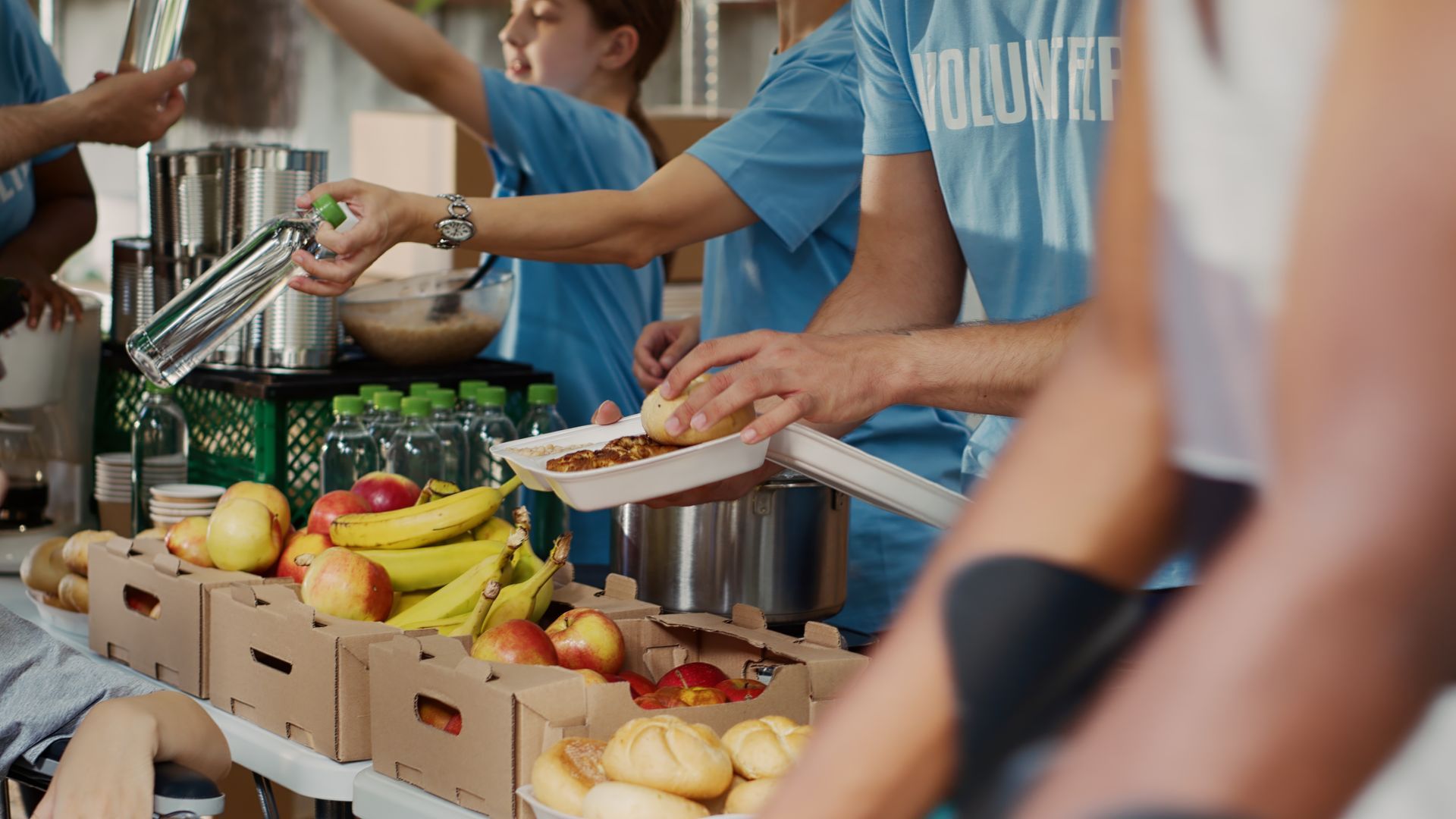 Volunteers serving fresh fruit and vegetables at a community food distribution table