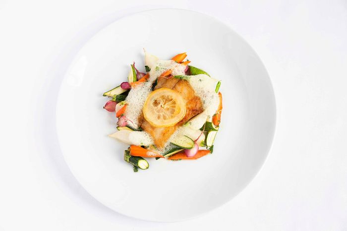 A white plate topped with a piece of fish and vegetables.