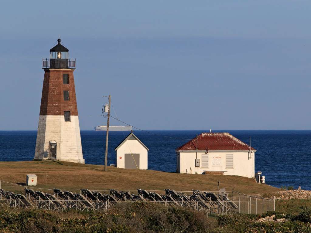 A lighthouse and a house on a hill with a full moon in the background.