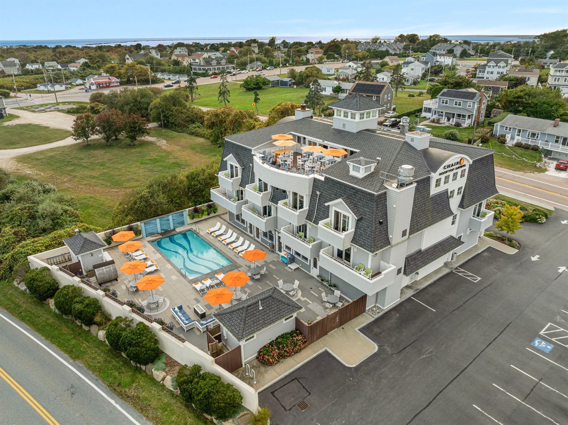 An aerial view of a hotel with a swimming pool and umbrellas.