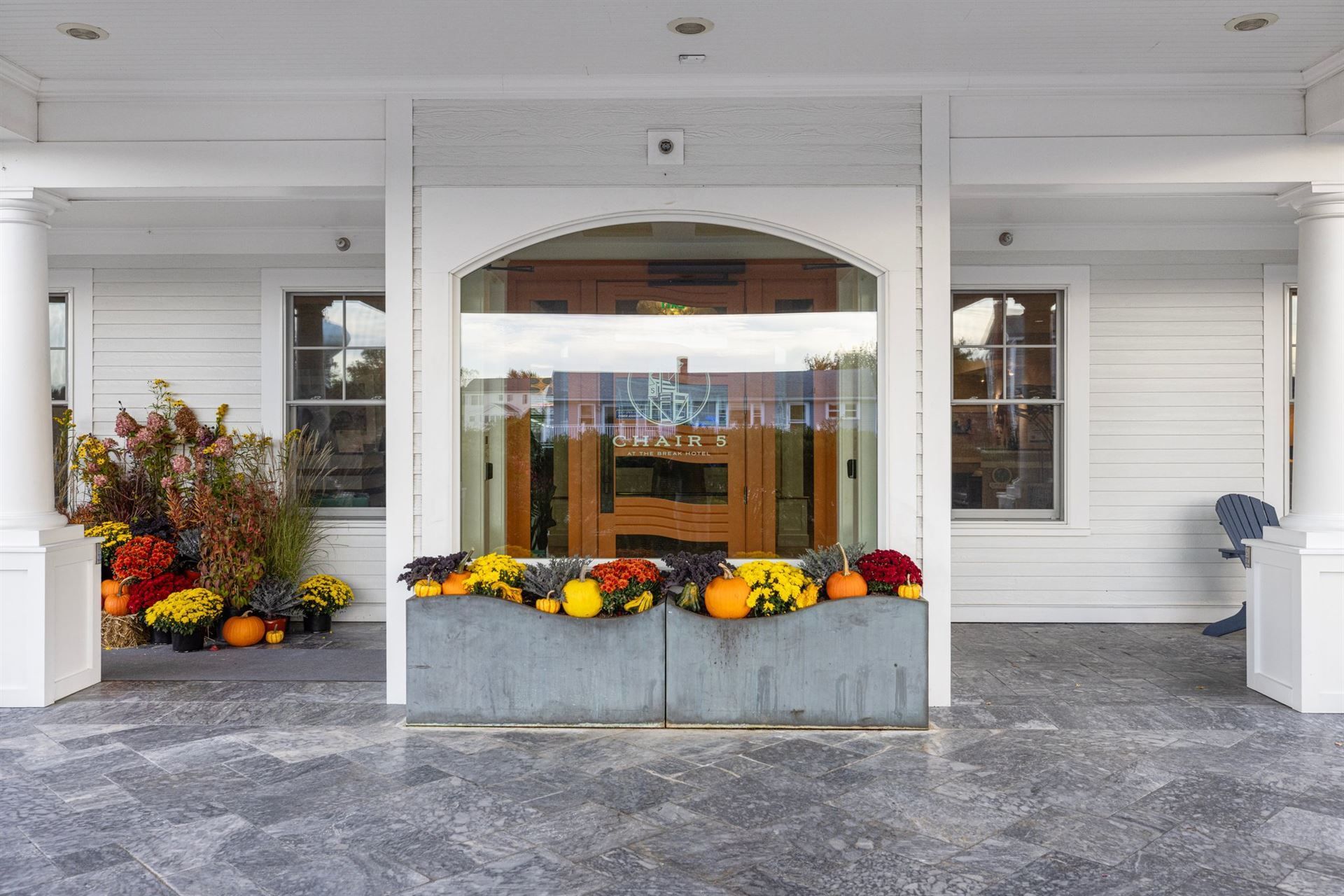 A white house with a porch decorated with pumpkins and flowers.