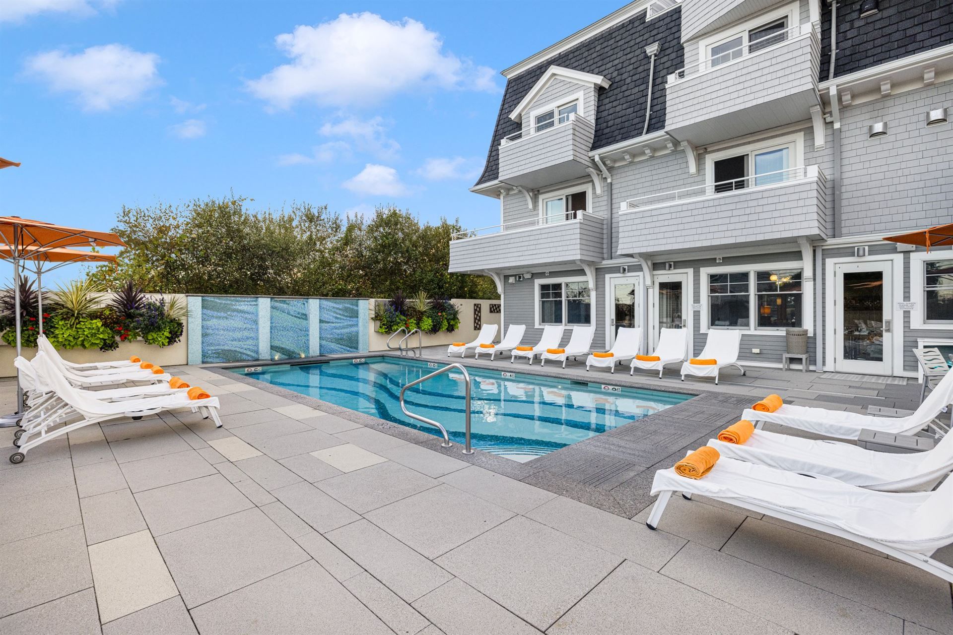 A large swimming pool is surrounded by lounge chairs and umbrellas.