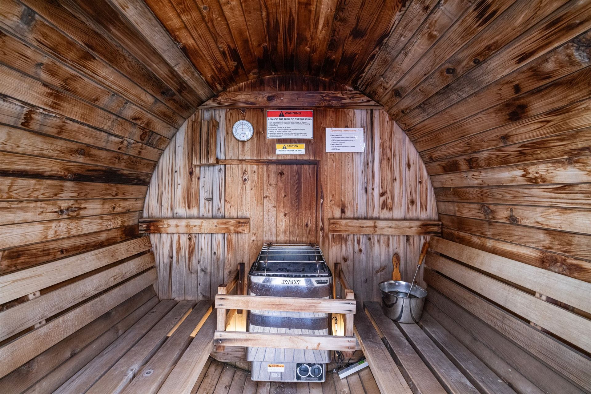 The inside of a wooden barrel sauna with a bucket on the floor.