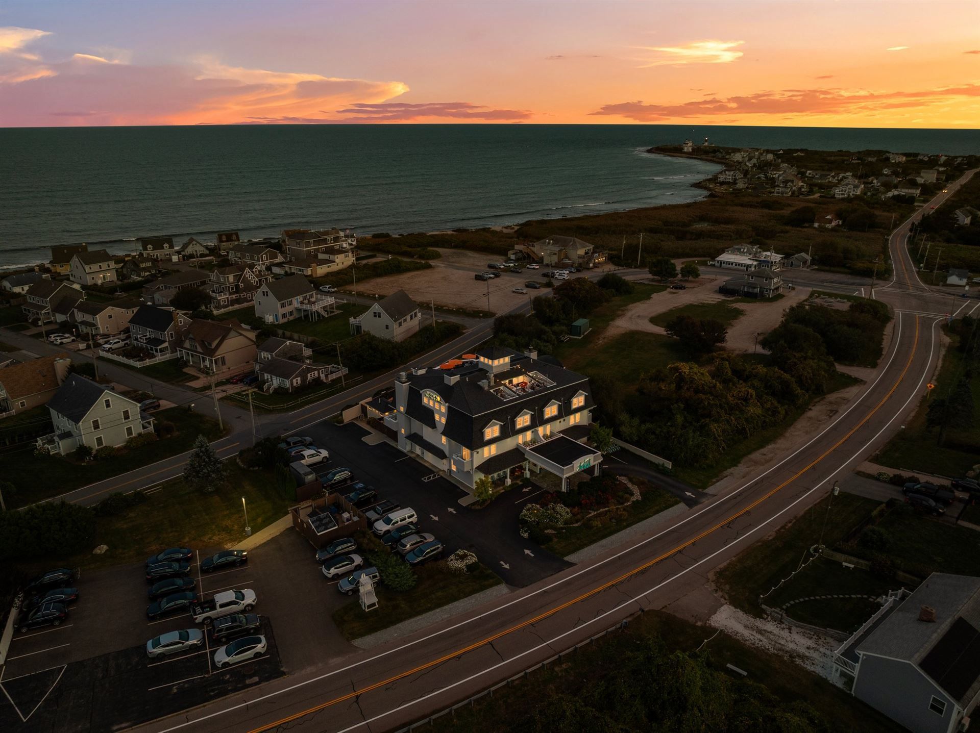 An aerial view of a small town near the ocean at sunset.