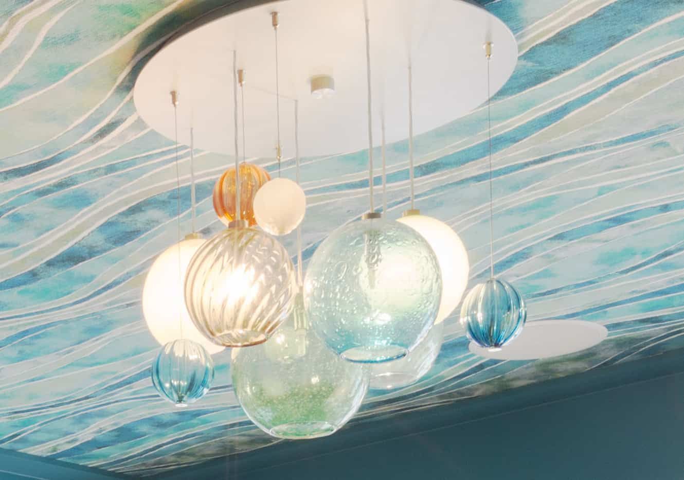 A chandelier with a painting on the ceiling is hanging from the ceiling.