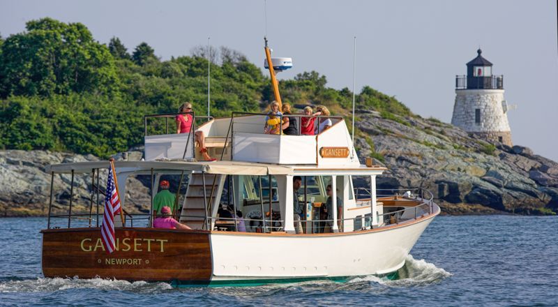 A boat named gavsett is floating on the water near a lighthouse