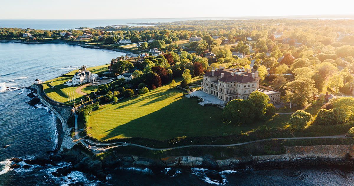 An aerial view of a large house on the shore of the Atlantic Ocean surrounded by trees.