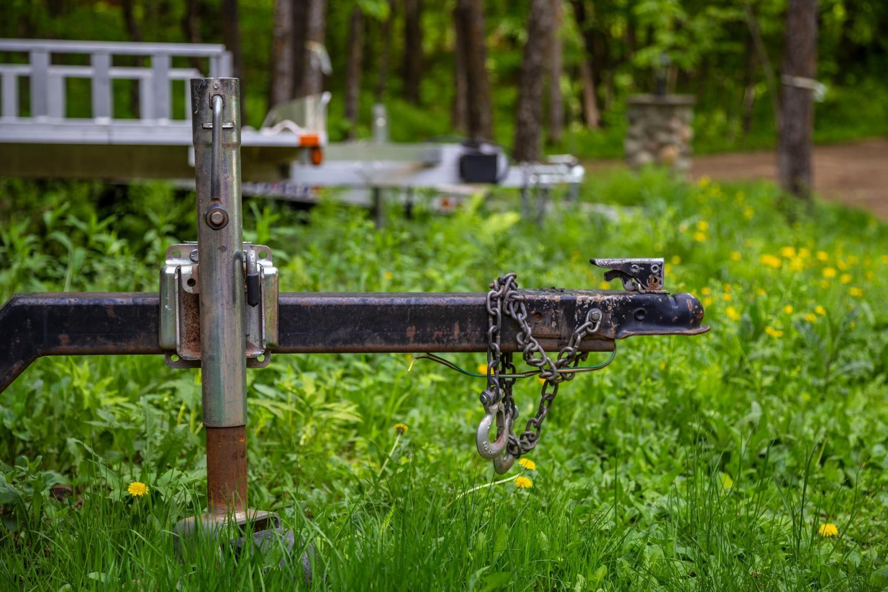 A trailer is parked in the grass in the woods.
