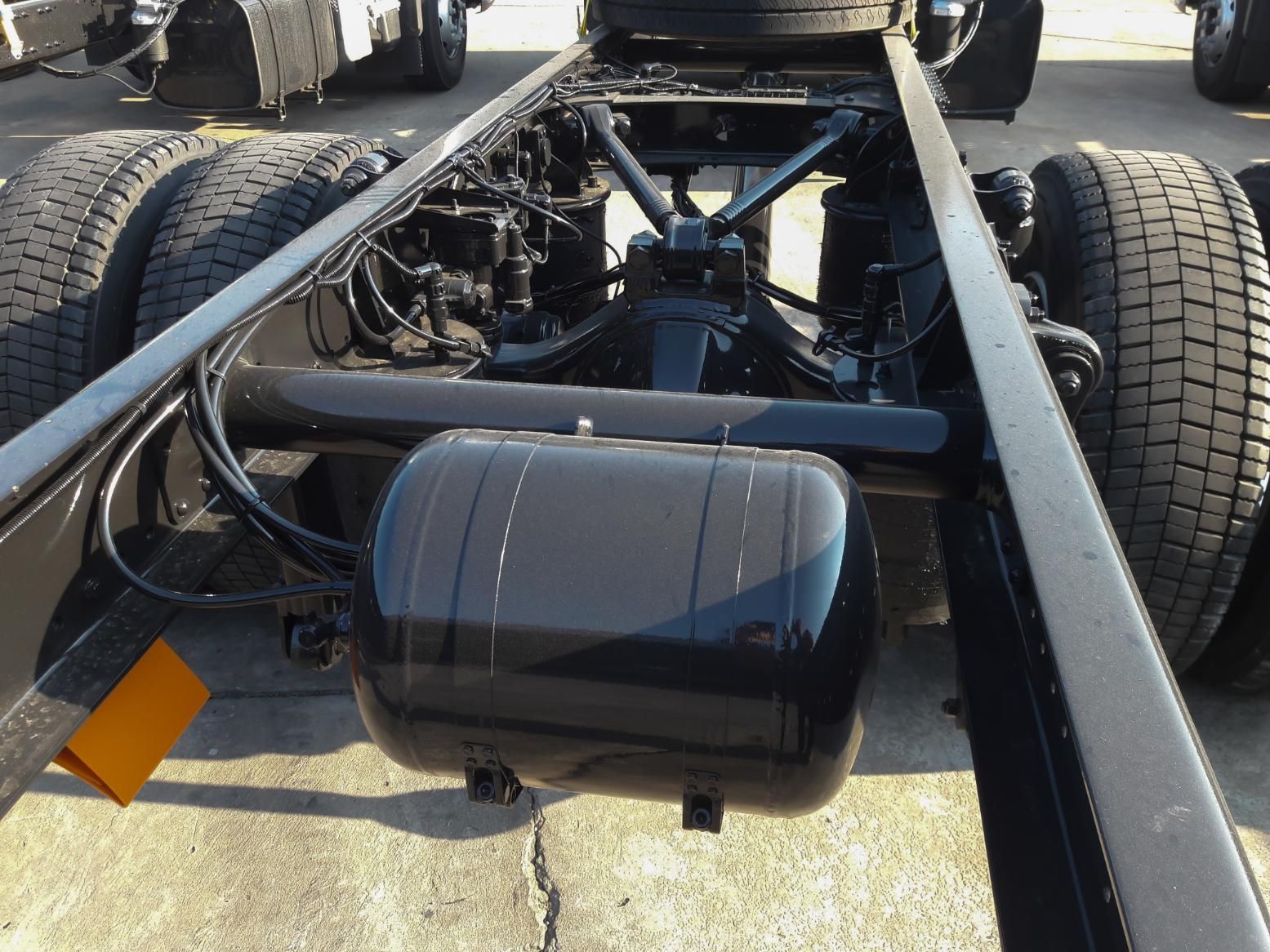 A black tank sits underneath a truck frame.