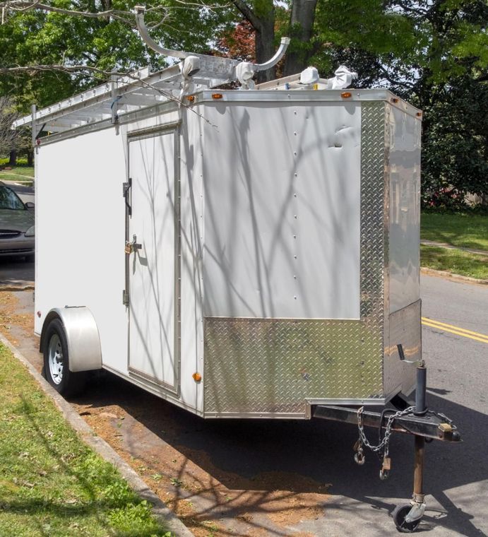 A white trailer is parked on the side of the road.