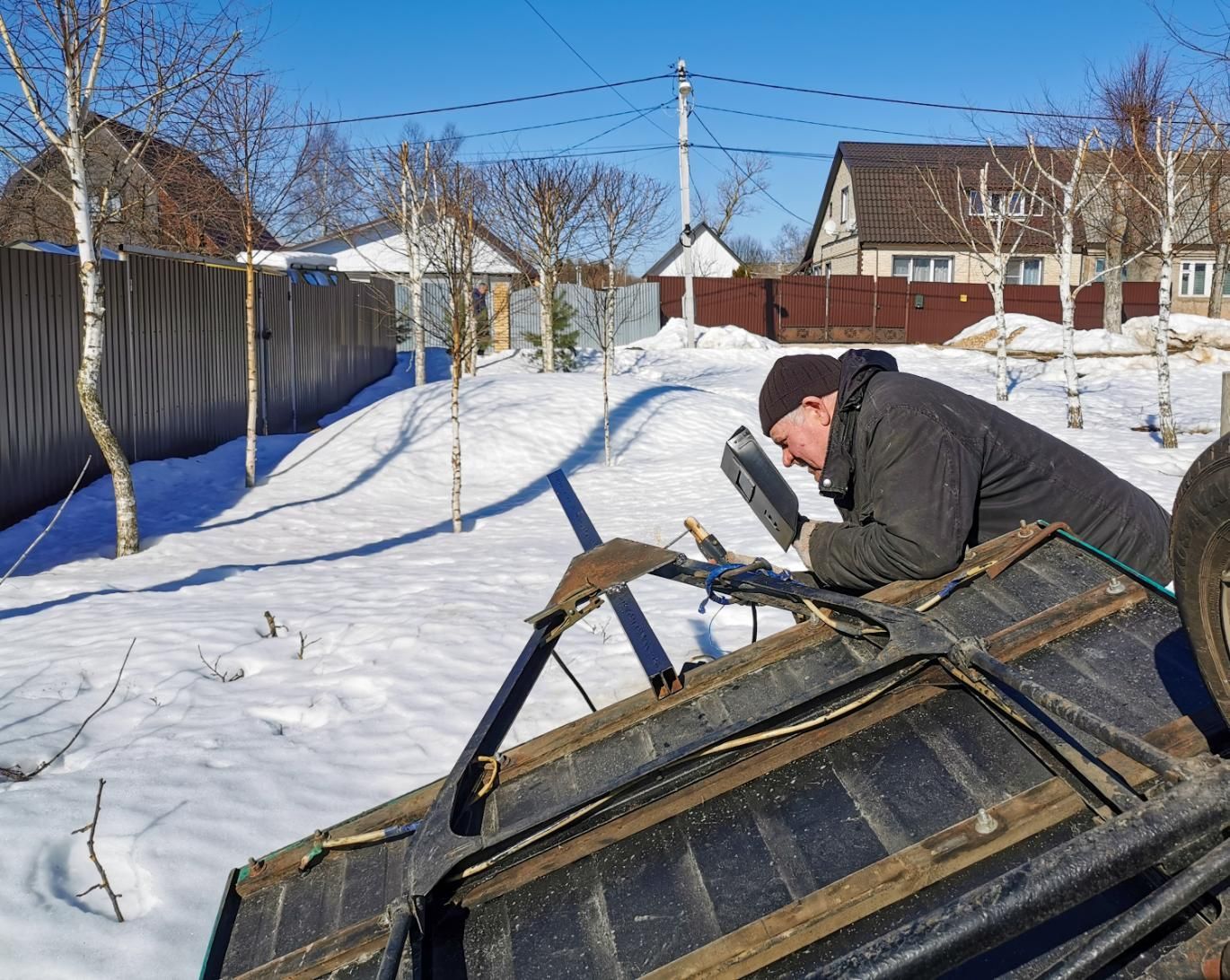 A man is working on the roof of a car in the snow.