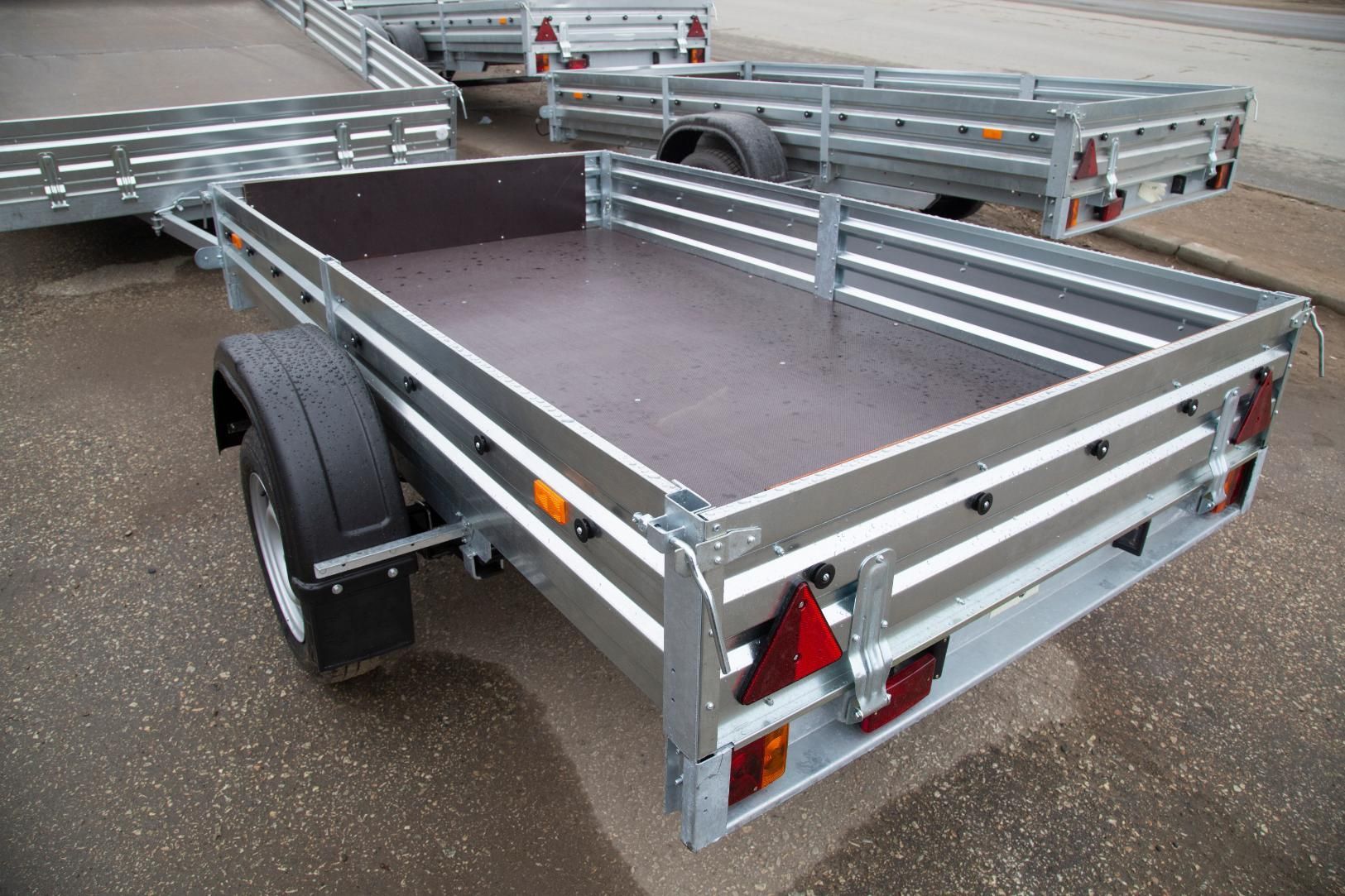 A trailer with a wooden floor is parked on the side of the road.