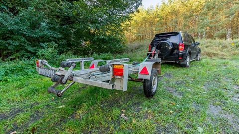 A car is towing a boat trailer in a grassy field.