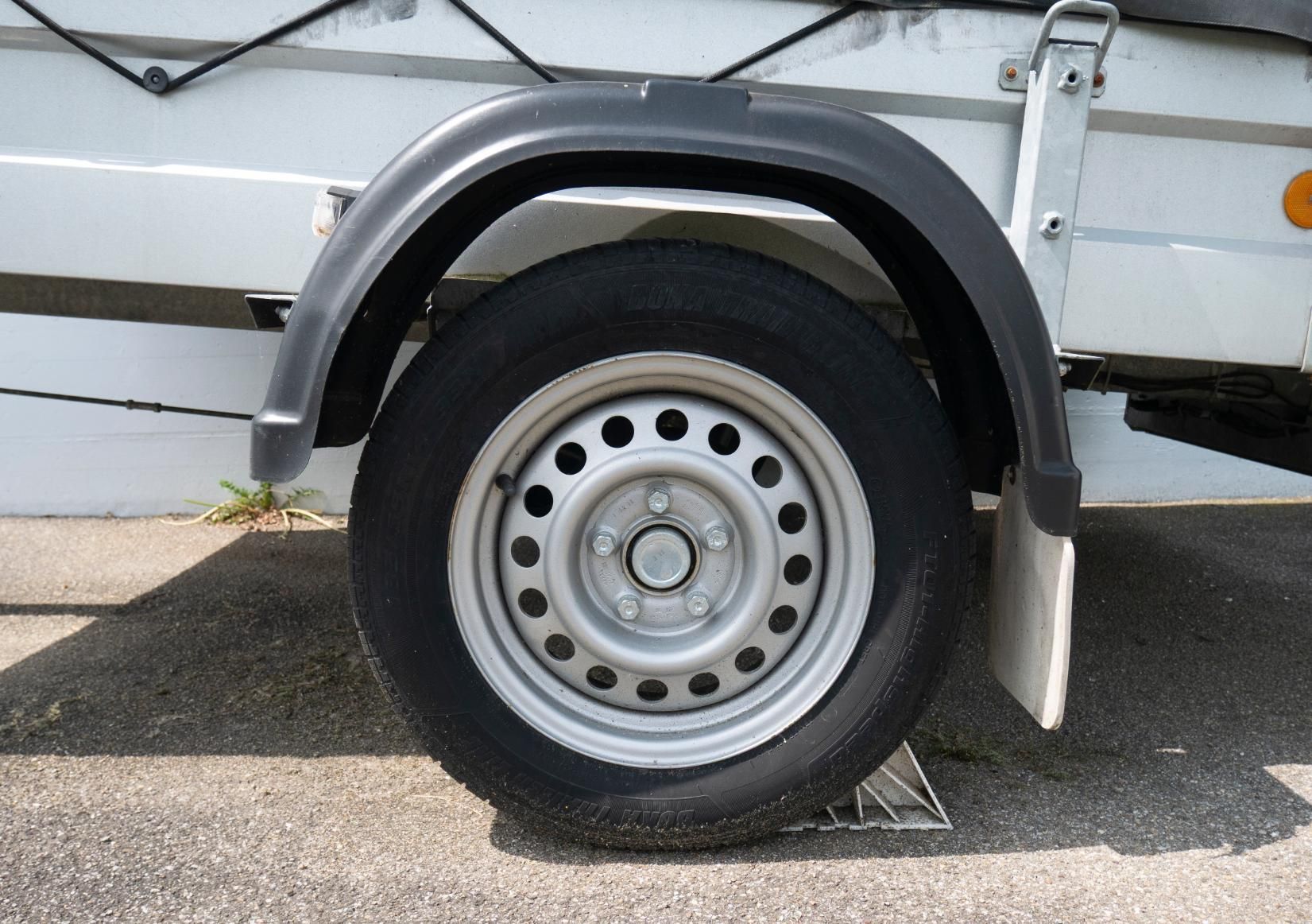 A close up of a trailer wheel on a road.