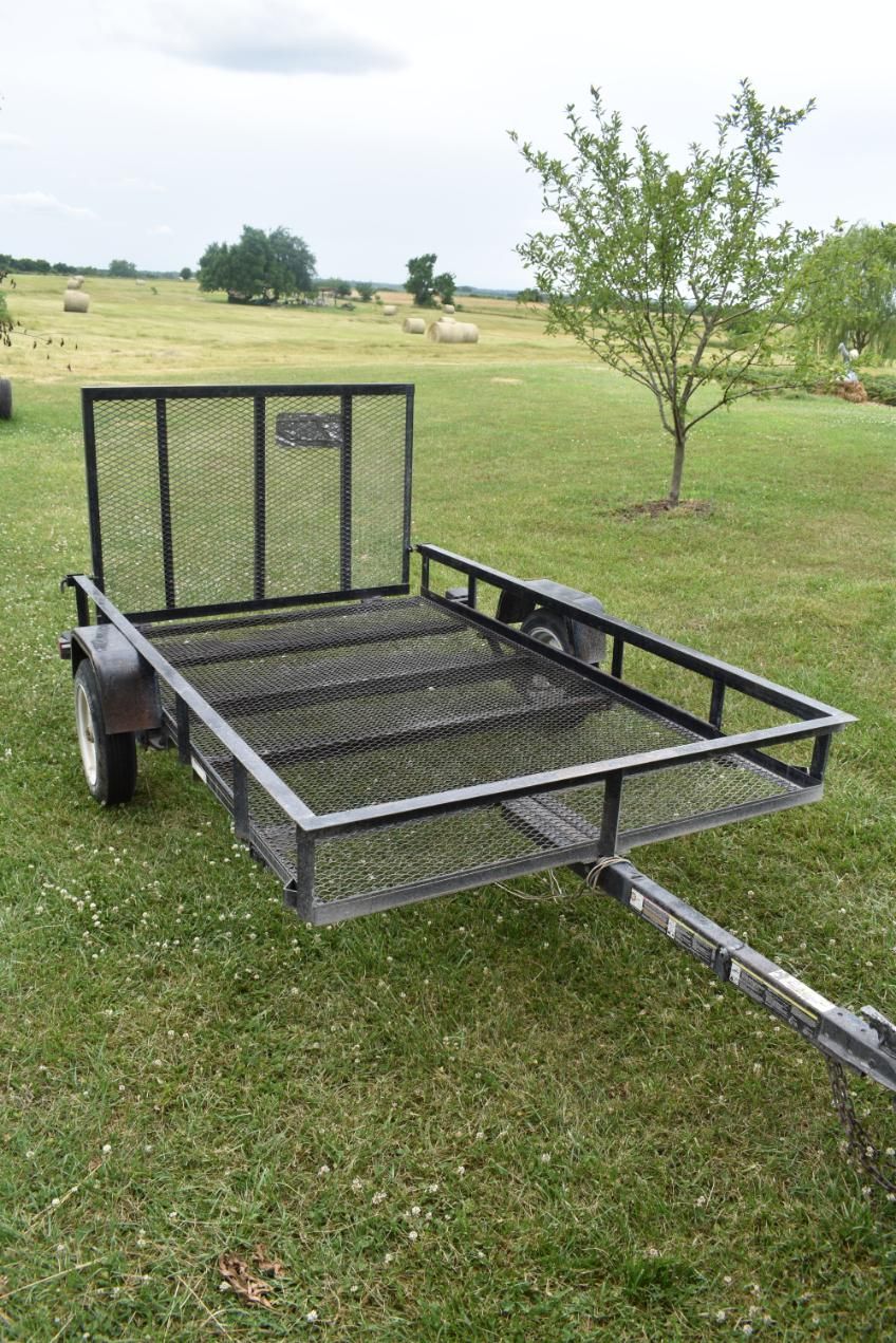 A small trailer is sitting on top of a lush green field.