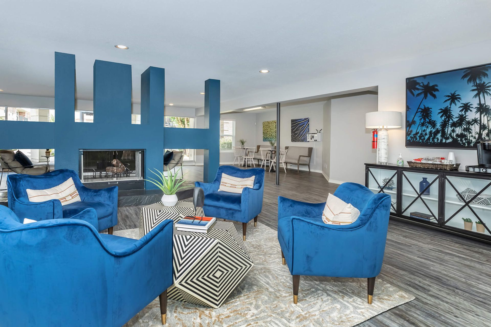 A room with blue chairs, a coffee table, and a fireplace at Baystone Apartments in Webster, TX.