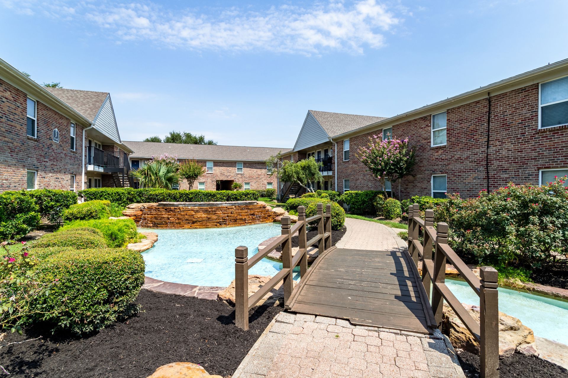 Townhouse exteriors with a green lawn, trees, and power lines against a partly cloudy sky.