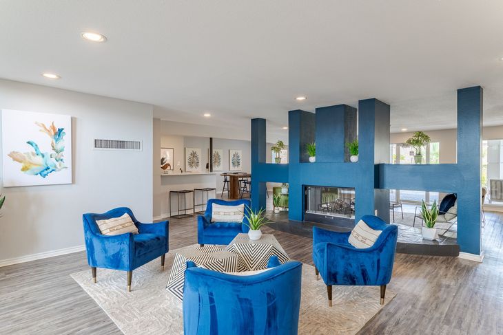 Cozy room with blue velvet chairs, fireplace, and a decorative black and white patterned ottoman.