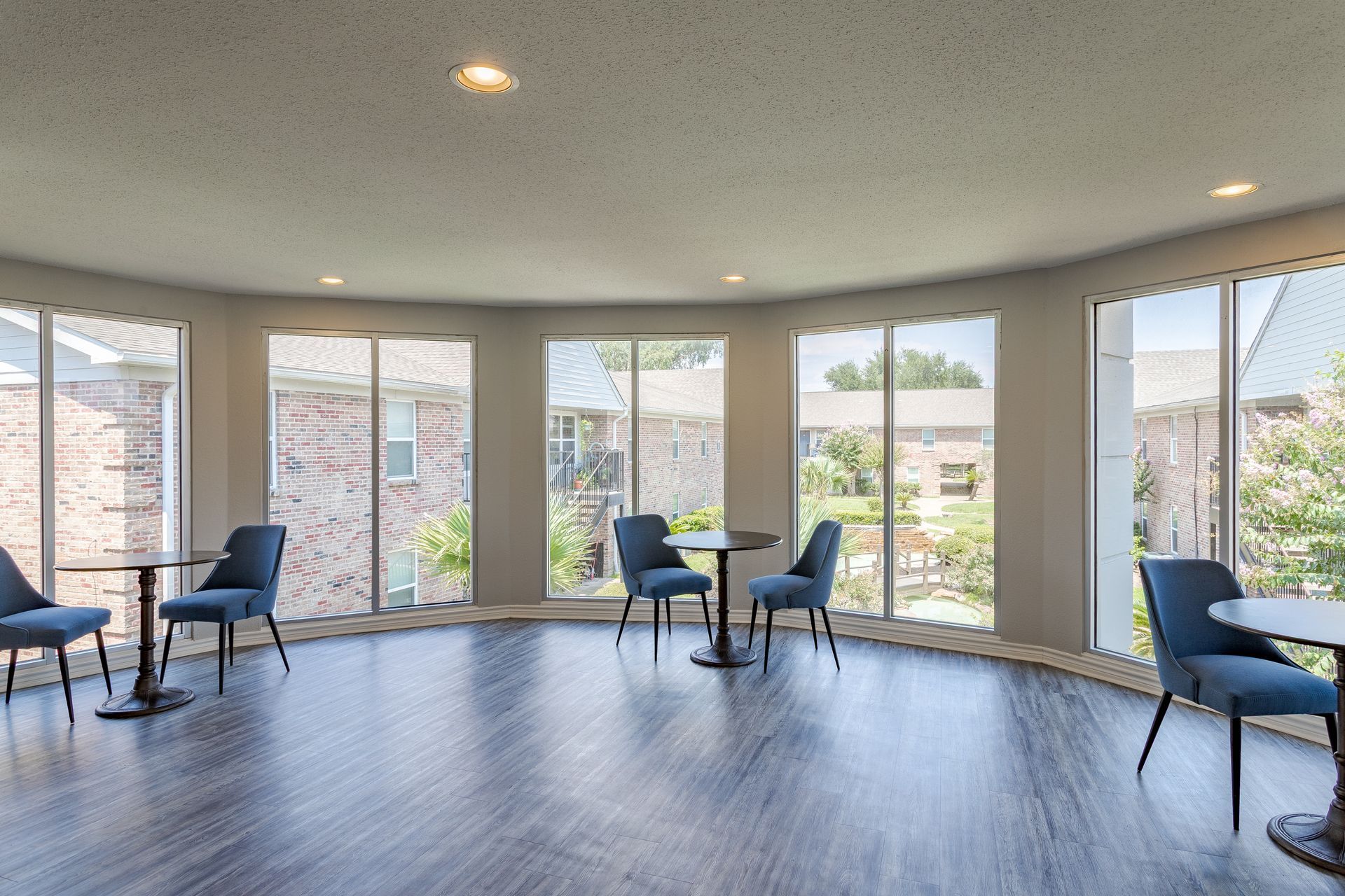 Brick apartment building with two blue doors, green lawn, and trees.