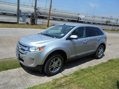 A silver ford edge is parked on the side of the road.