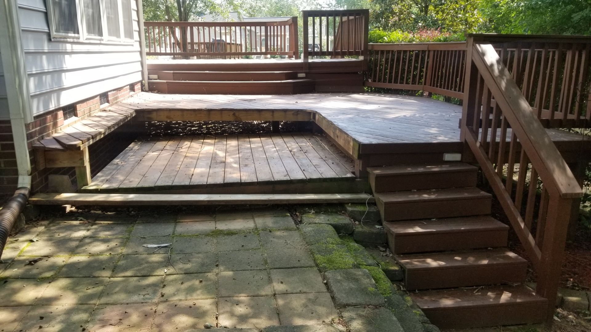 A wooden deck with stairs leading up to it next to a house.
