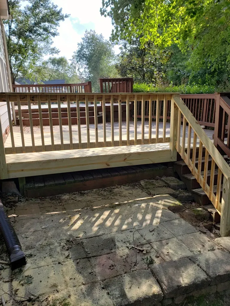 A wooden deck with stairs leading up to it and a wooden railing.